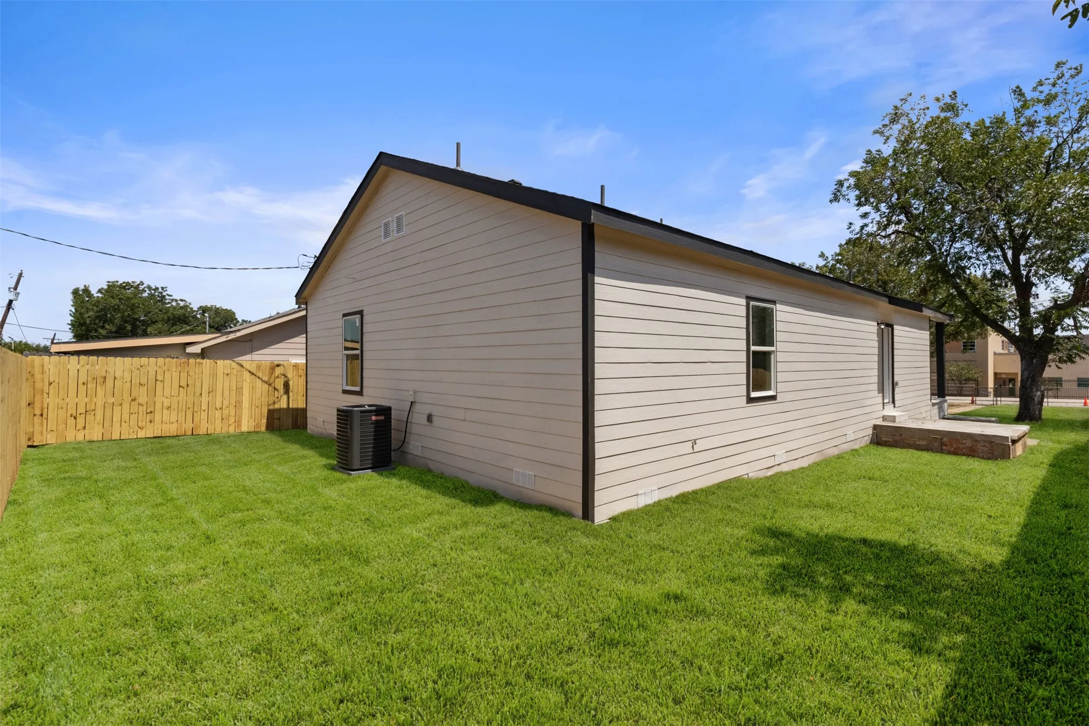 Expansive backyard featuring a manicured lawn, new wooden fencing, and a concrete patio