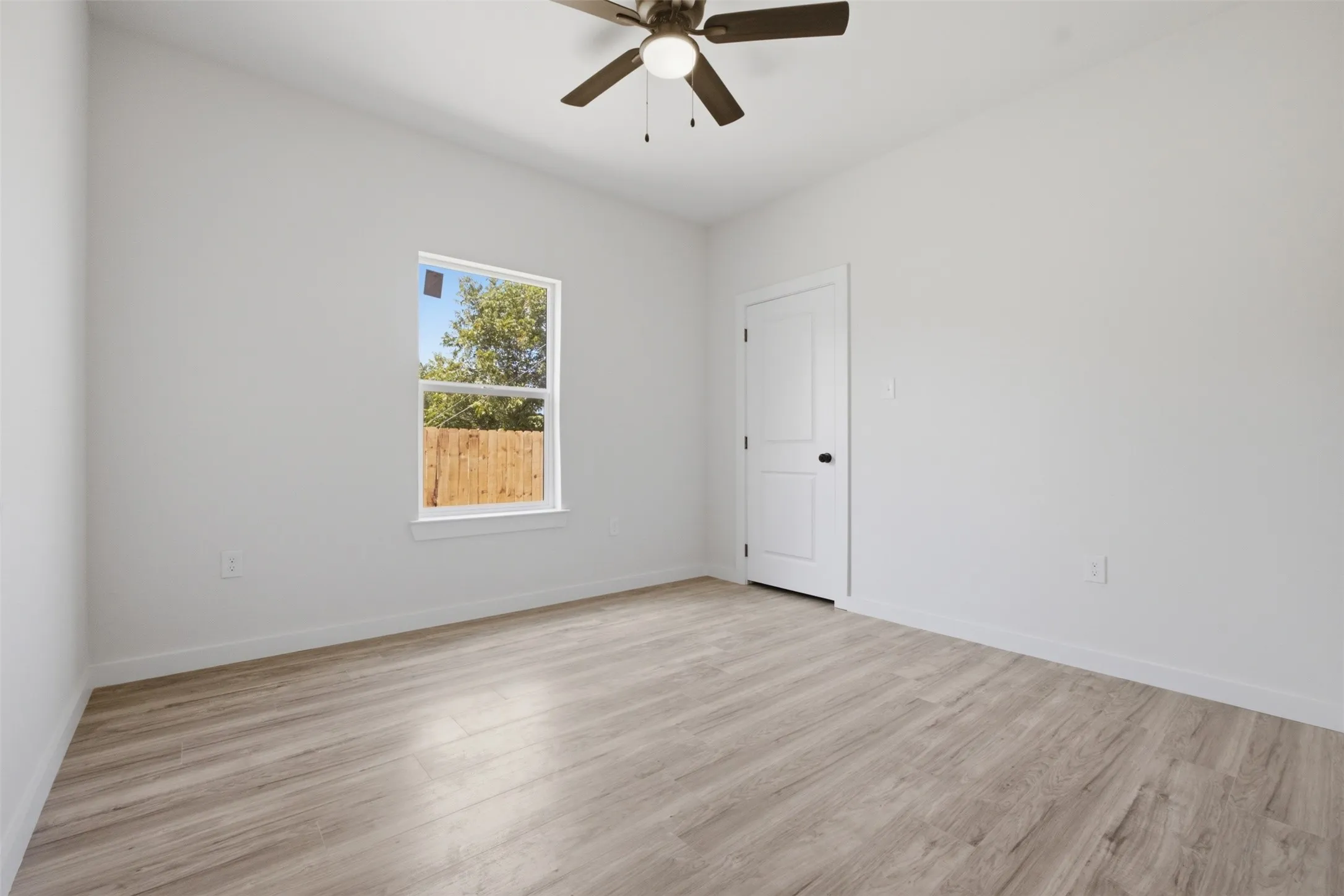 Neutral wall paint, wood-finish flooring, ceiling fan, and white trim