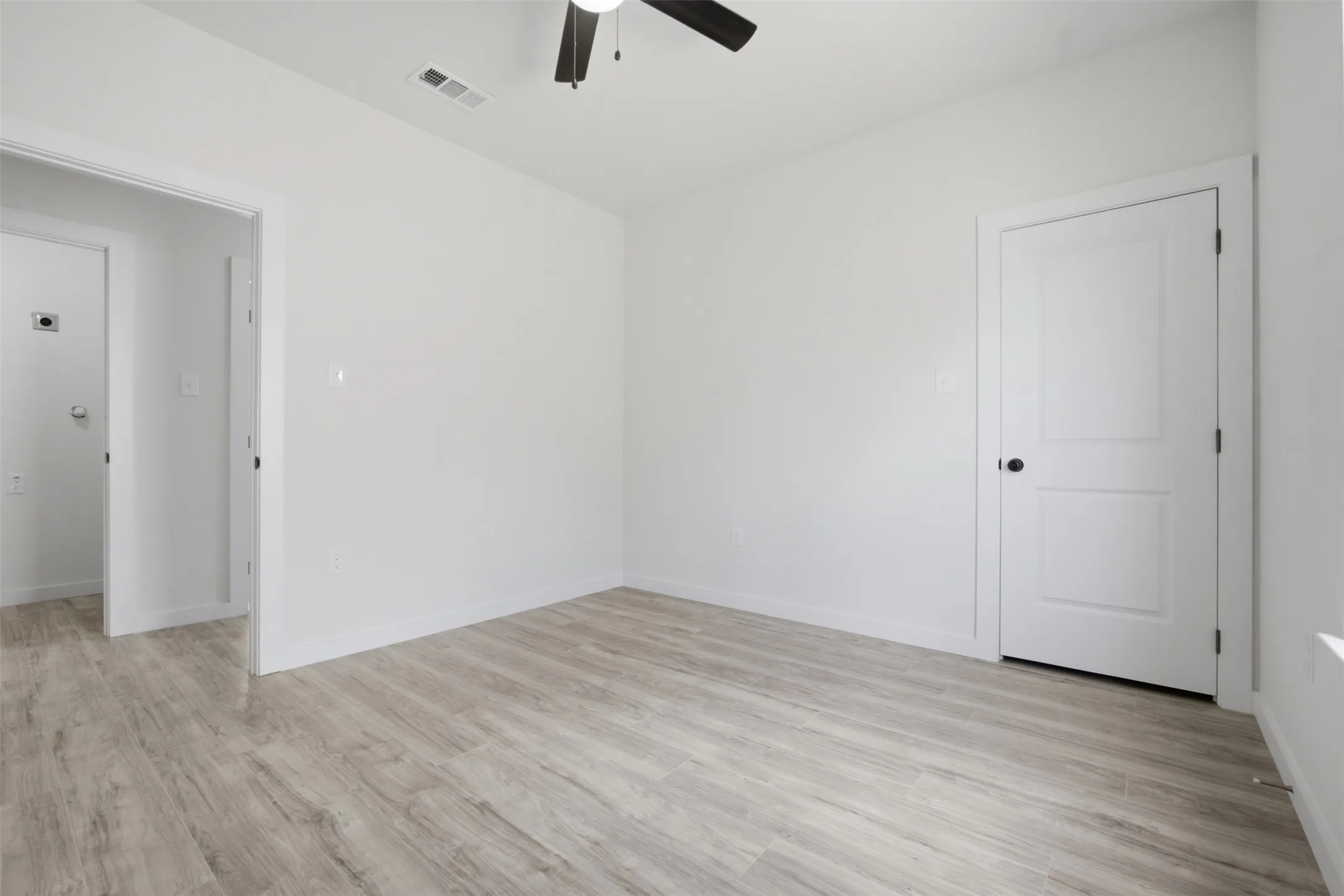 Light wood-finish flooring with white walls and trim