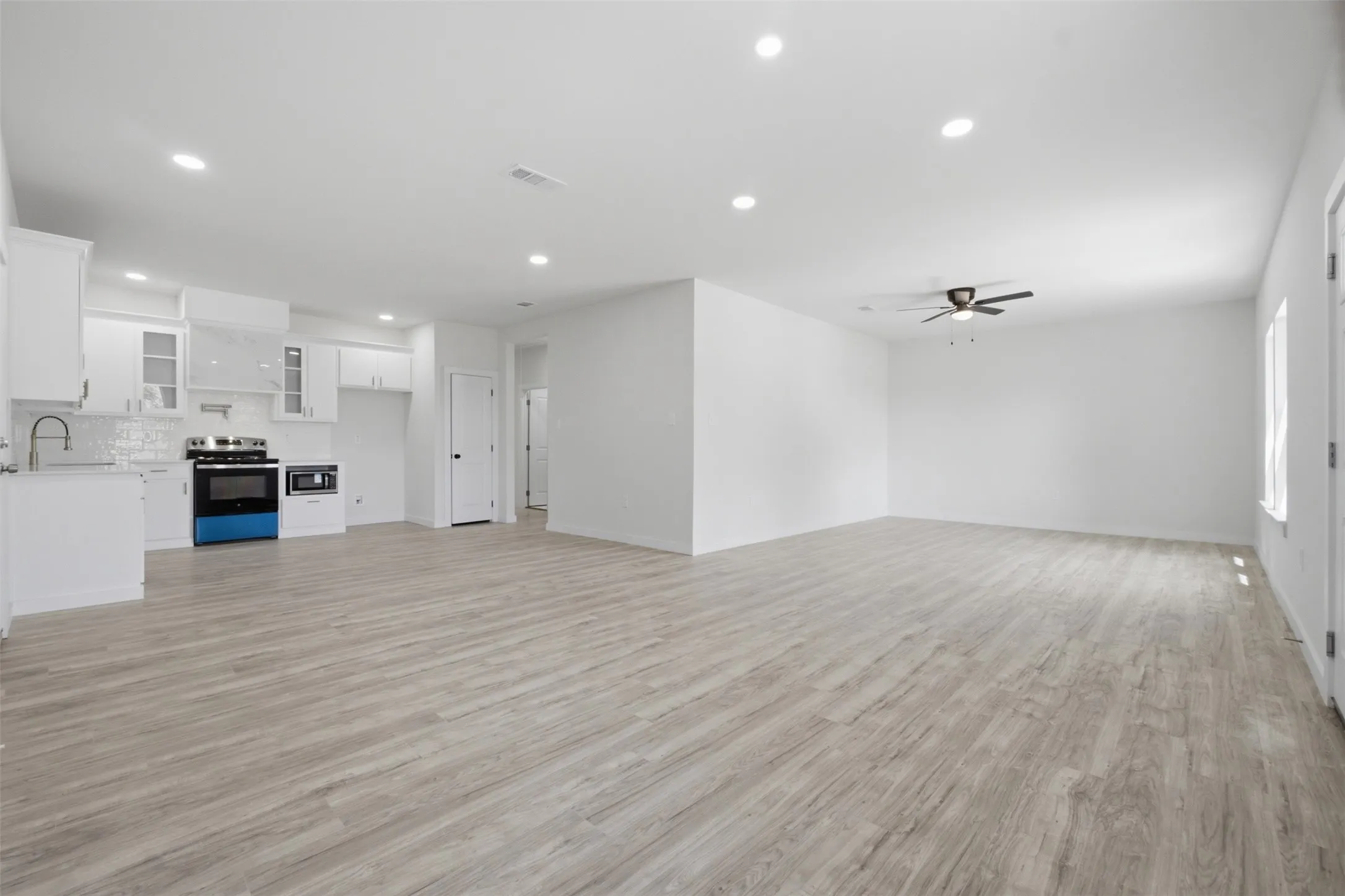Open-concept living space with wood-finish flooring, recessed lighting, and a ceiling fan