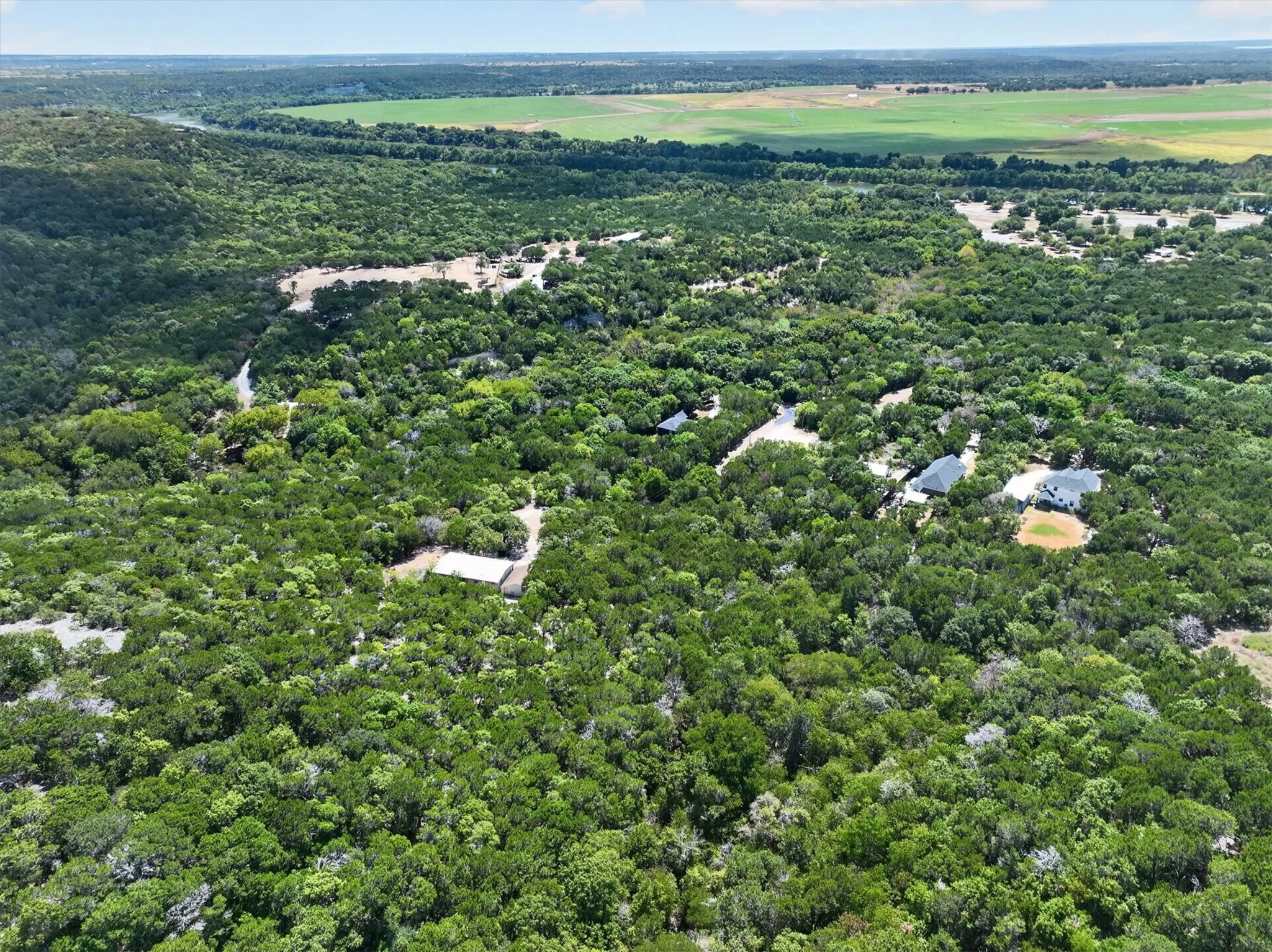 Expansive acreage featuring abundant mature trees, multiple structures, and a natural watercourse