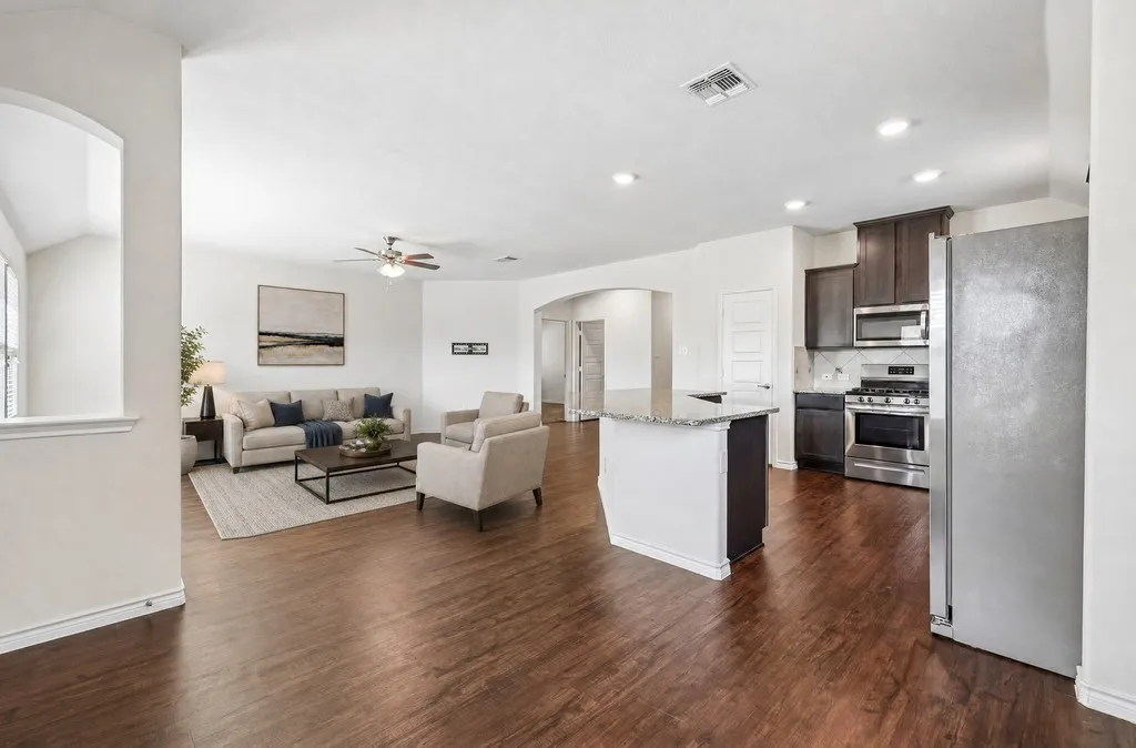 Open-concept living area with wood-finish flooring, a ceiling fan, and recessed lighting, virtually staged