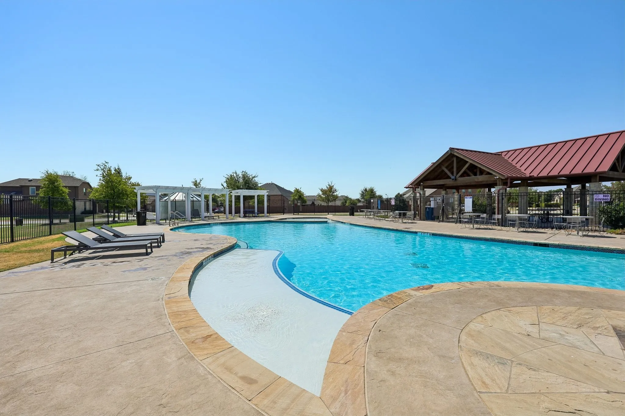 Community pool featuring a shallow entry, paved surround, and covered pavilion with seating
