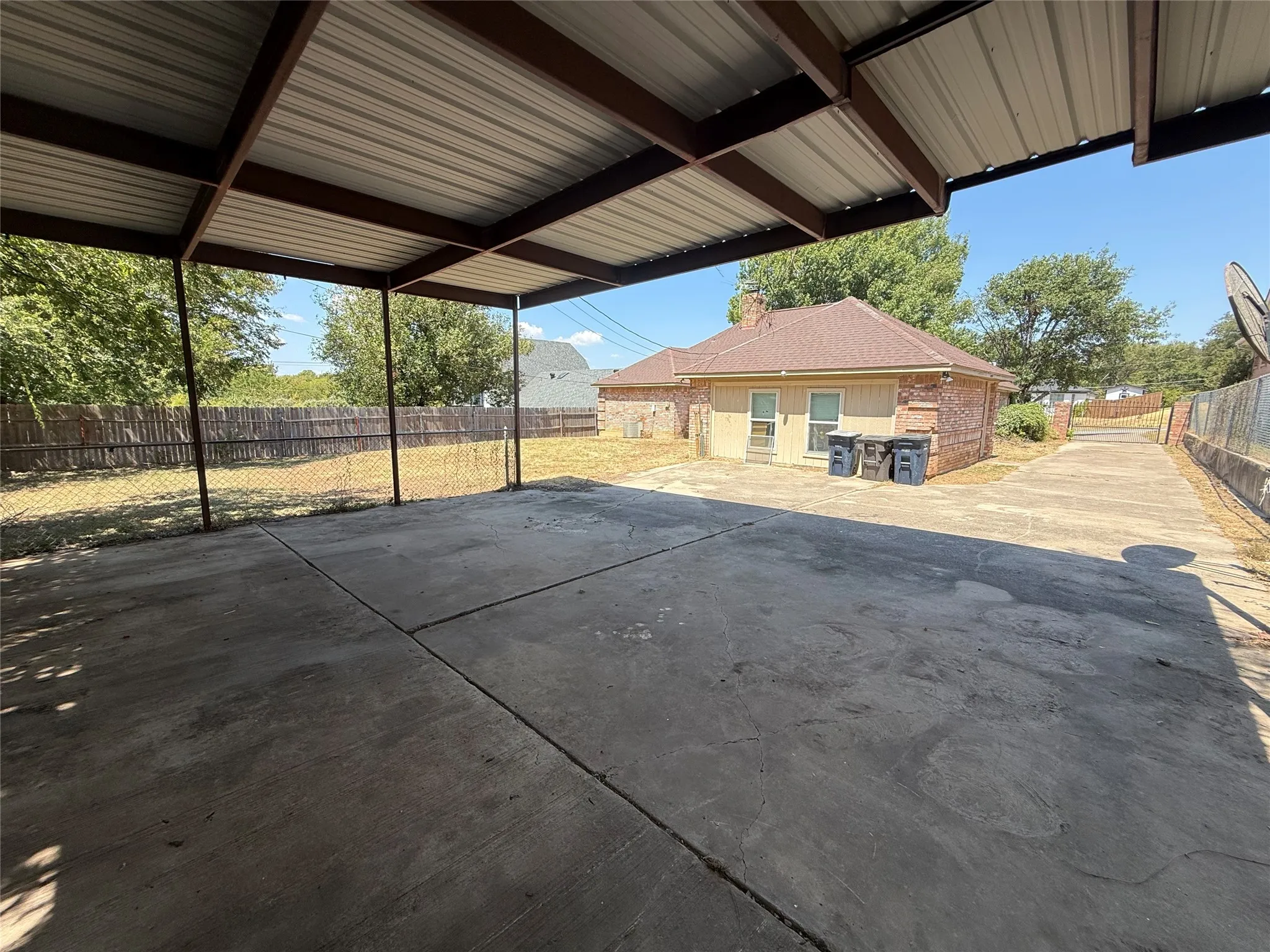 Carport in back of home with drivethrough driveway on side