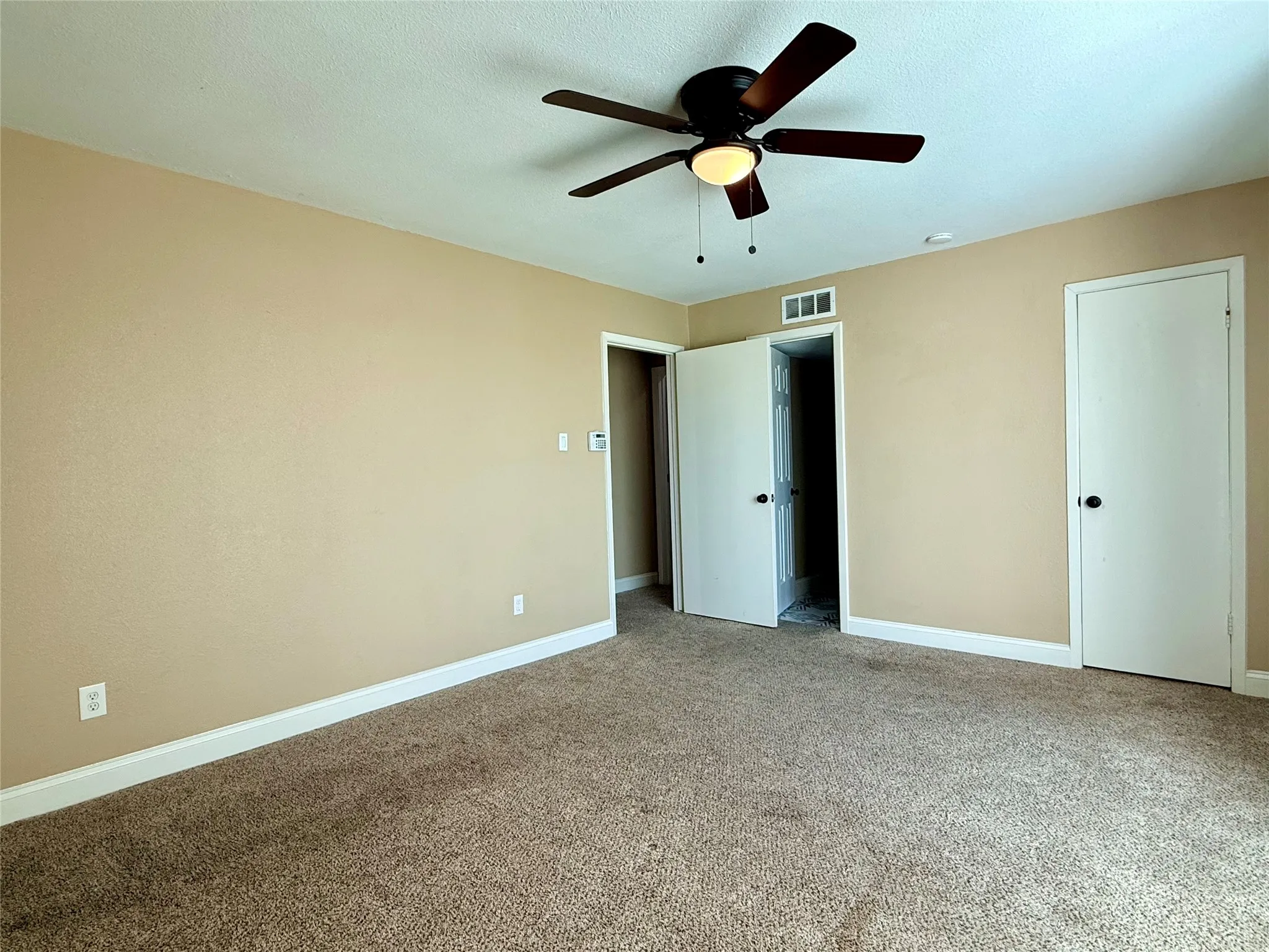 Warm neutral wall paint, ceiling fan with integrated lighting, brown carpet flooring, white trim, and white doors