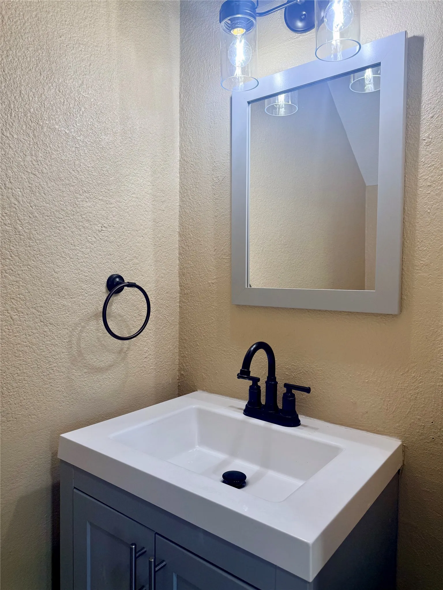Recessed vanity with a white integrated sink, matte black faucet, and a wall-mounted rectangular mirror