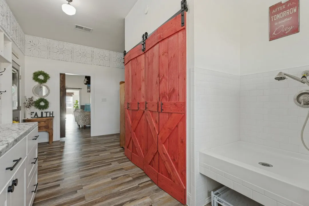 Dog wash and space for your washer and dryer.  Behind the barn doors is additional storage. Washer and dryer are to the right of the dog wash. Doorway leads into the living area.