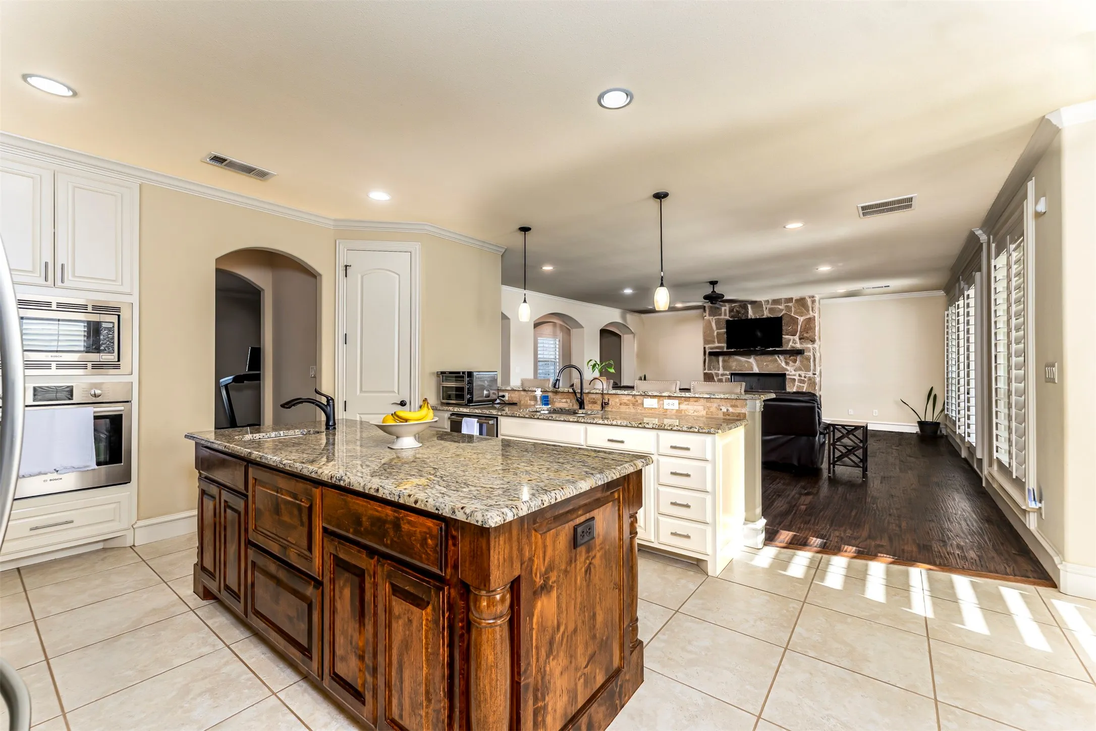 Kitchen with a large wood-finish island, stone countertops, stainless steel built-in appliances, and recessed lighting