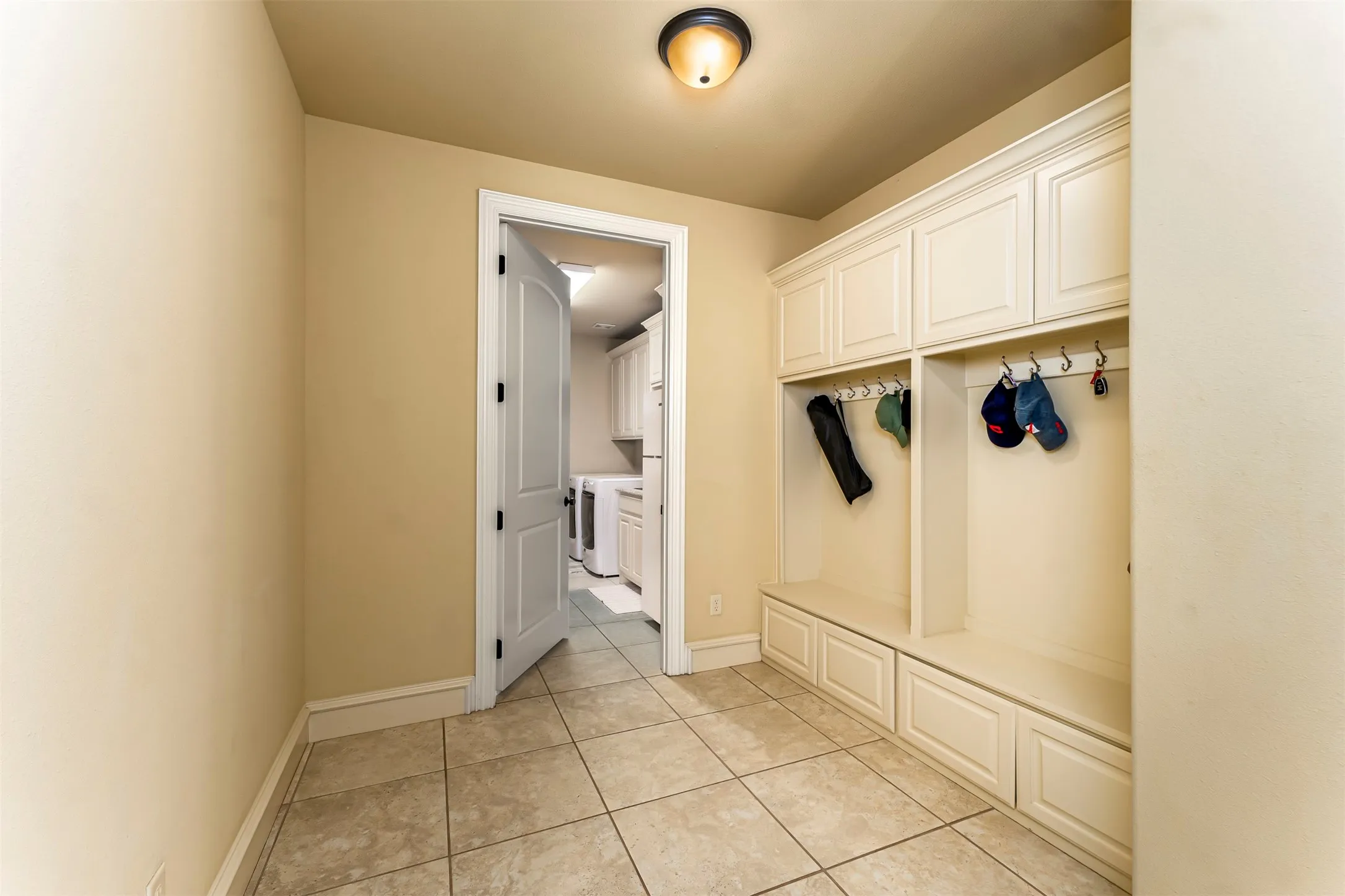 Built-in storage solutions with upper cabinetry and lower drawers, coat hooks, and durable tile flooring