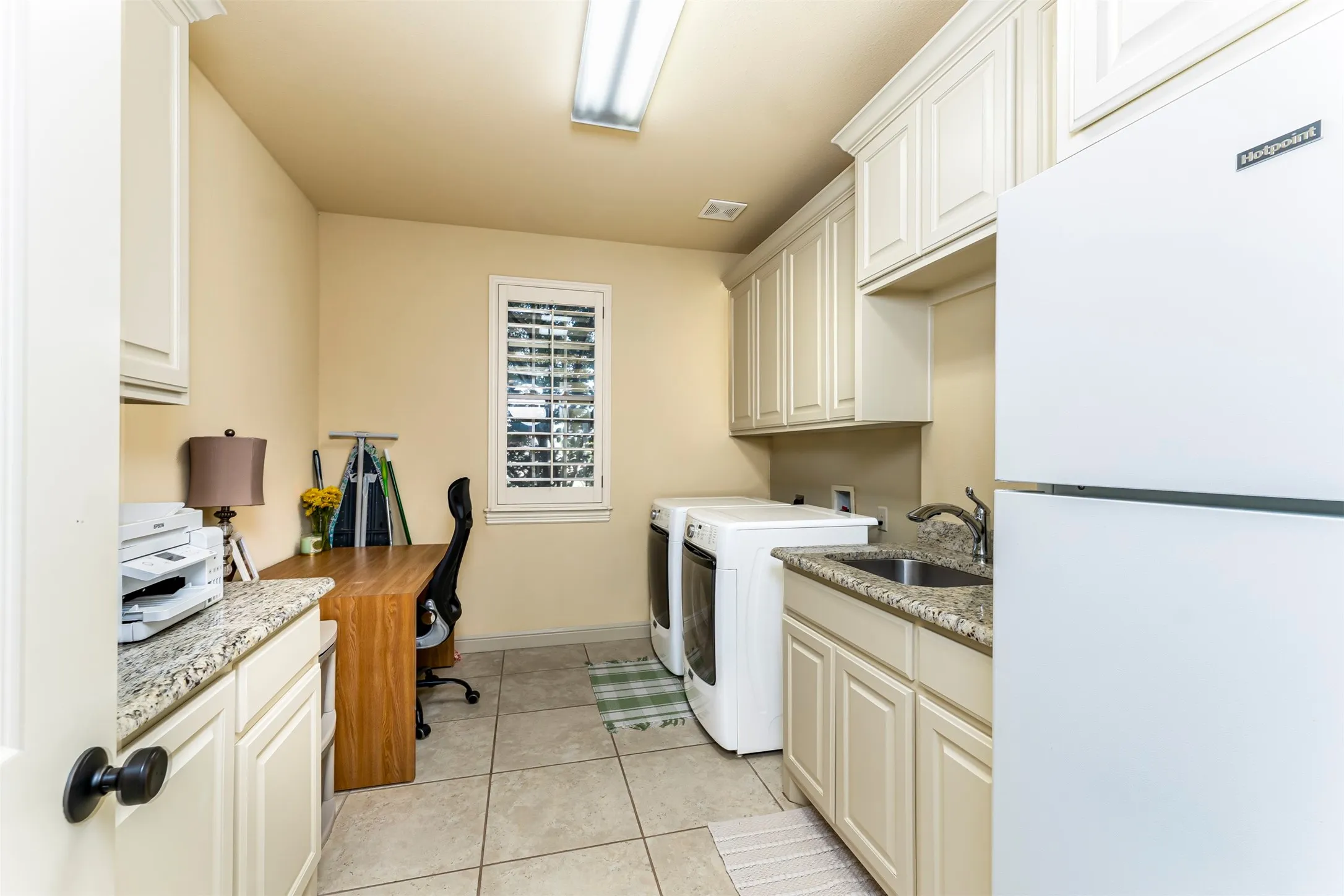 Utility room with tile flooring, built-in cabinetry, granite-style countertops, and a stainless steel sink