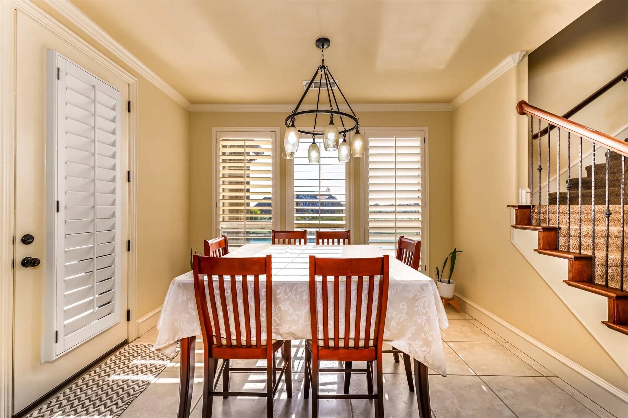 Dining area with tile flooring, crown molding, and plantation shutters