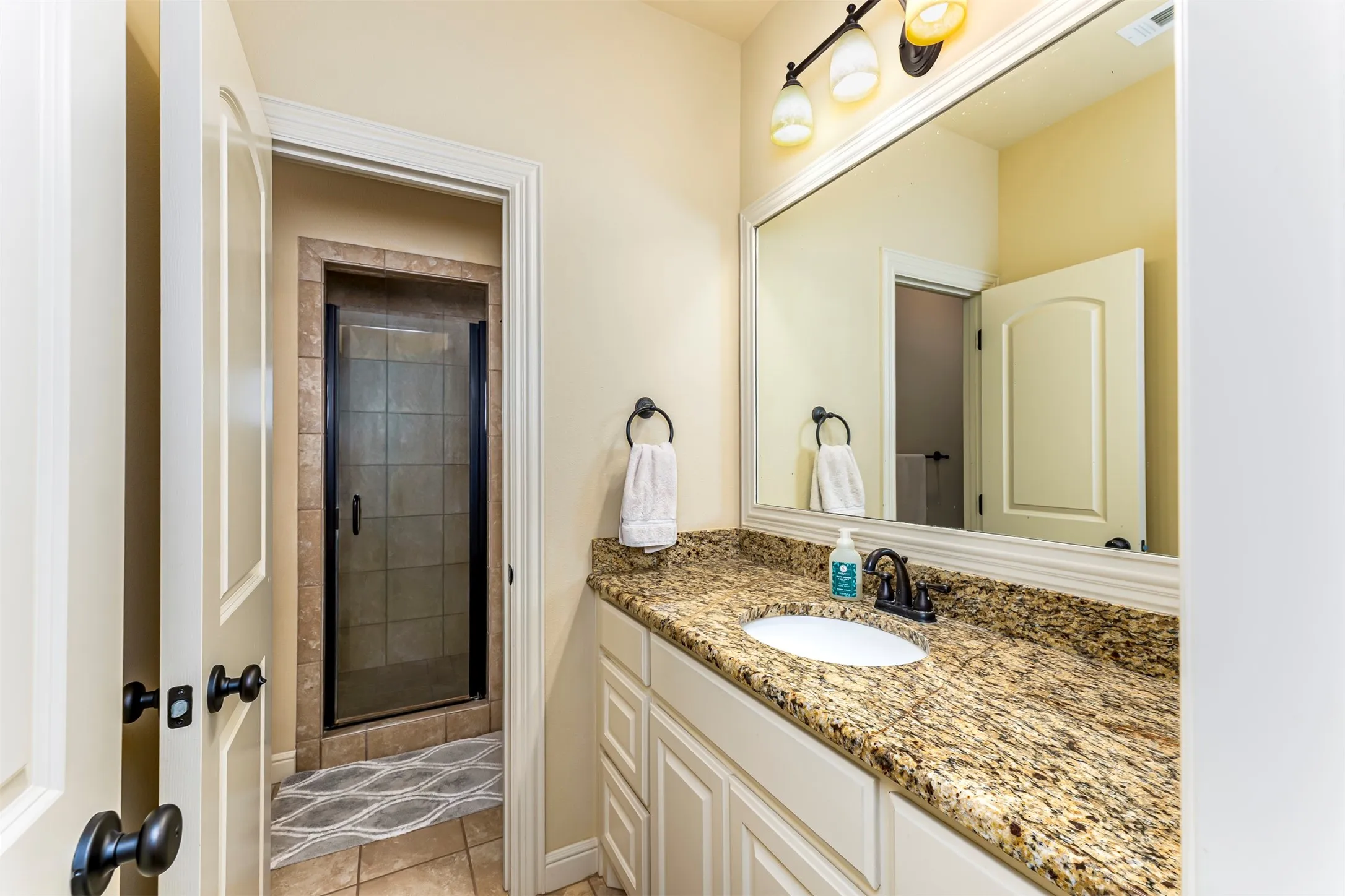 Bathroom featuring a single vanity with stone countertop, undermount sink, and dark bronze fixtures