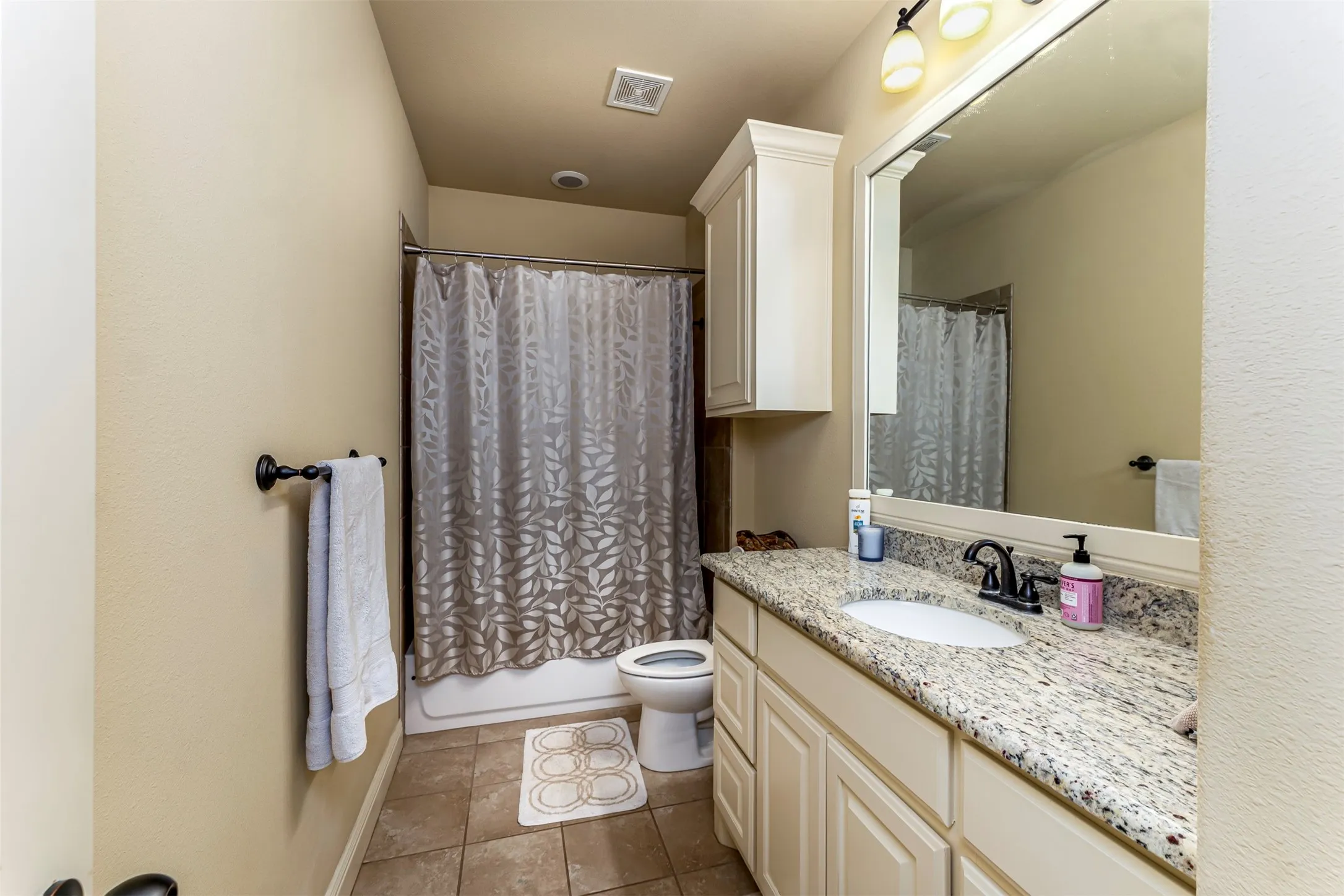 Bathroom featuring a single vanity with a light-toned countertop, a built-in medicine cabinet, and a shower-tub combination