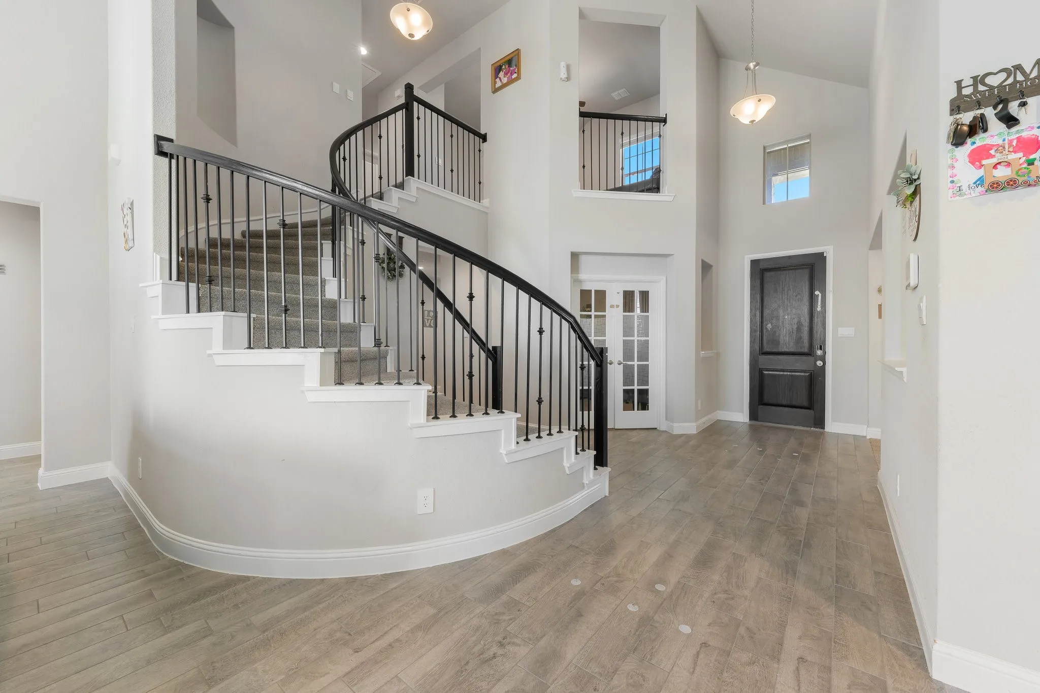 Foyer with high vaulted ceiling, wood finished floors, and stairs