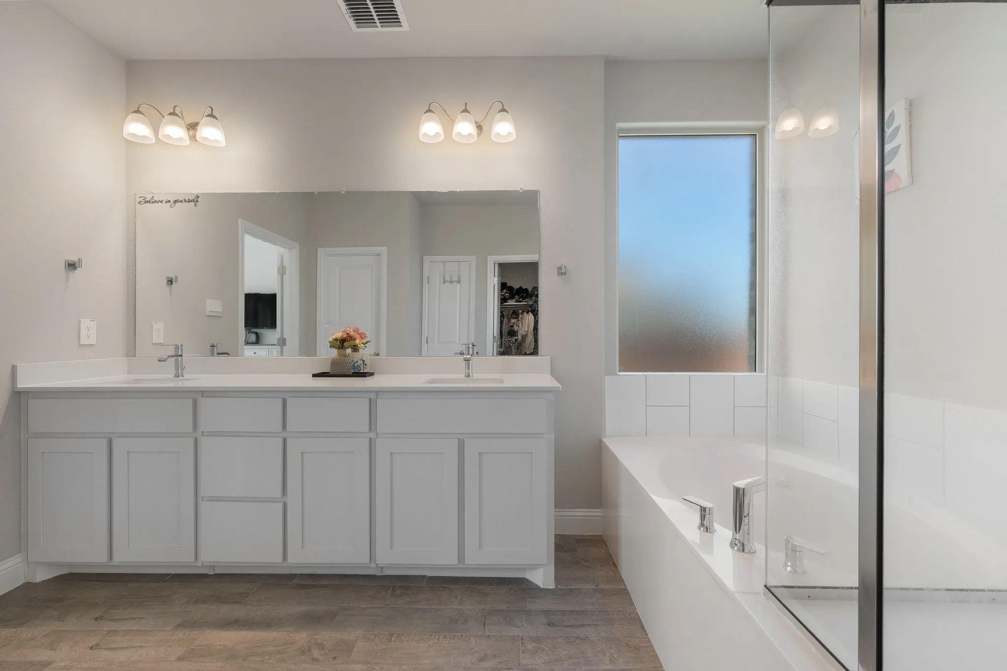 Bathroom with double vanity, a tub, and light wood finished floors