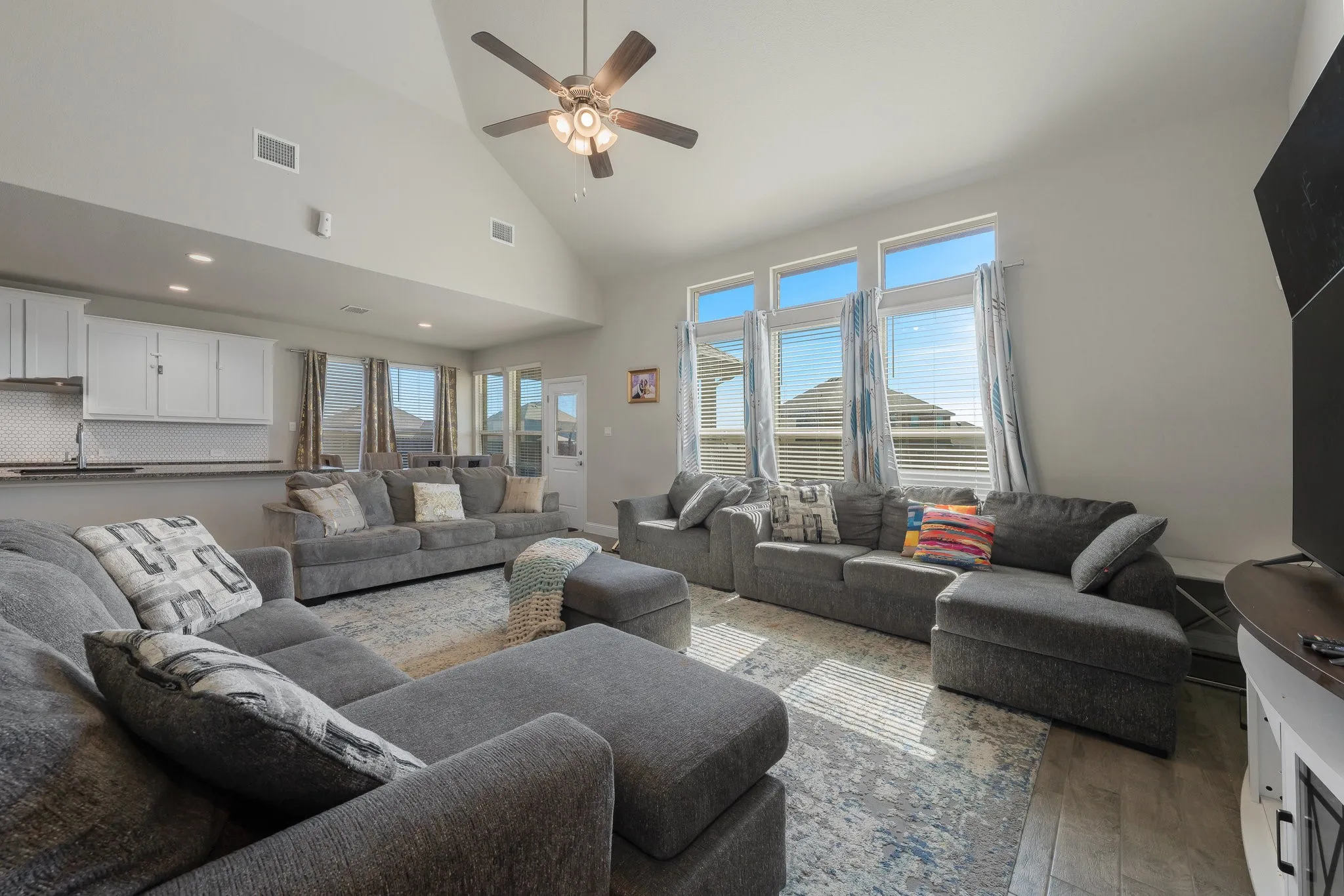 Living room with high vaulted ceiling, wood finished floors, and a ceiling fan