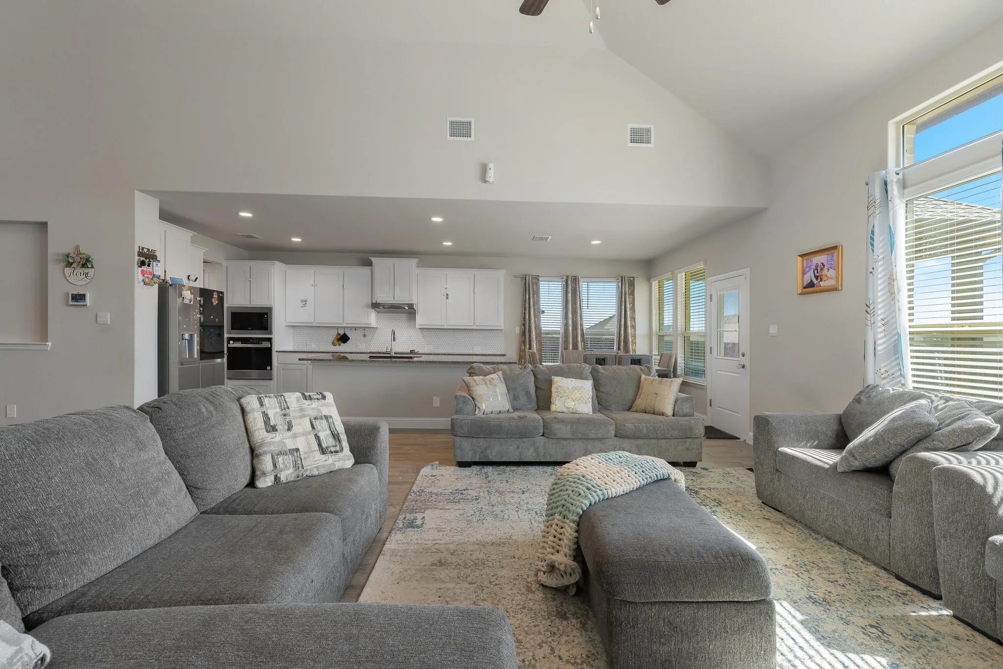 Living area featuring high vaulted ceiling, healthy amount of natural light, a ceiling fan, wood finished floors, and recessed lighting