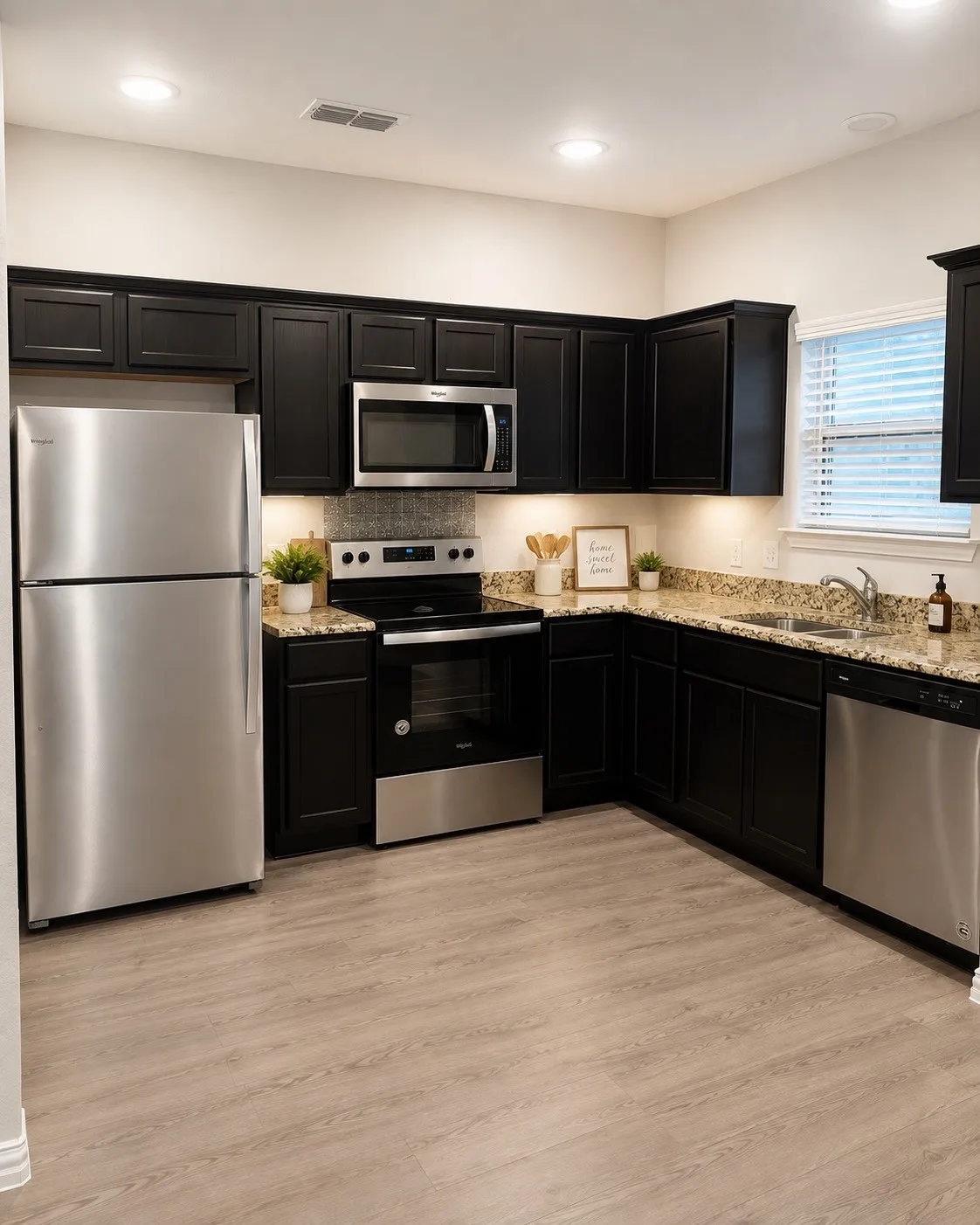 Kitchen featuring dark wood-finish cabinetry, stainless steel appliances, speckled countertops, wood-finish flooring, and recessed lighting