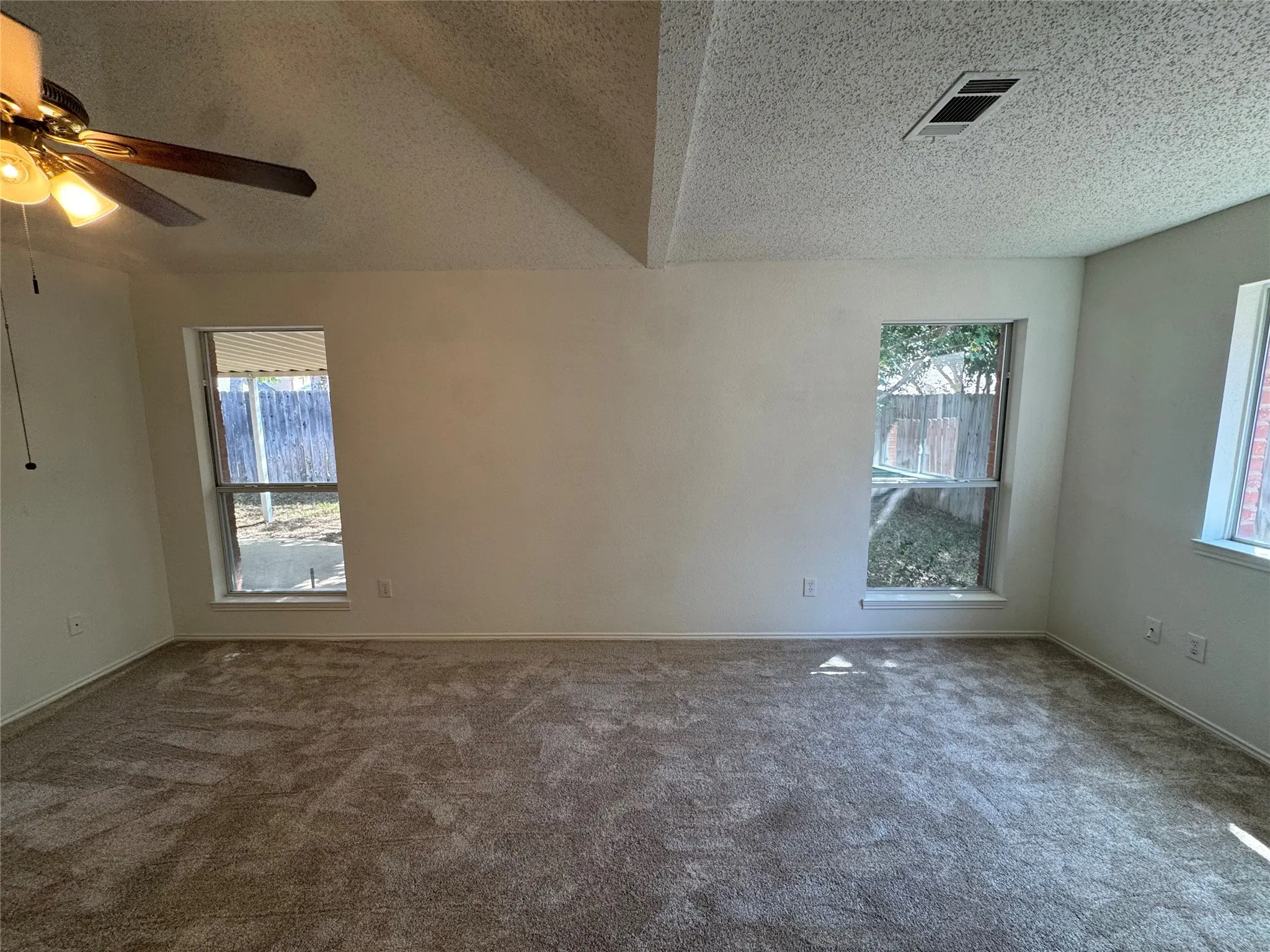 Wall-to-wall carpeting and multiple windows complement the neutral wall finishes