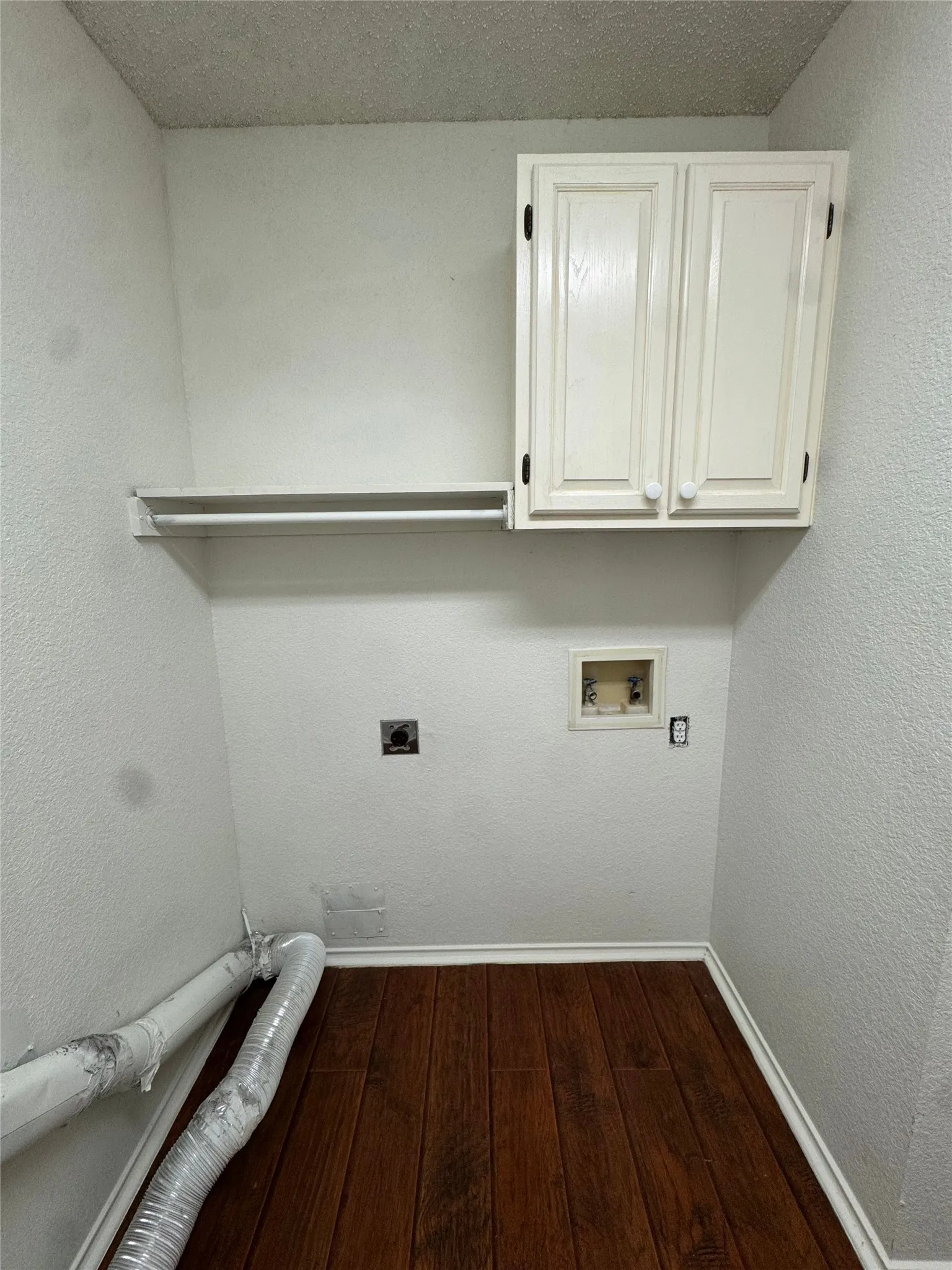 Wood-finish flooring with baseboards, overhead cabinetry, and an integrated clothes hanging rod