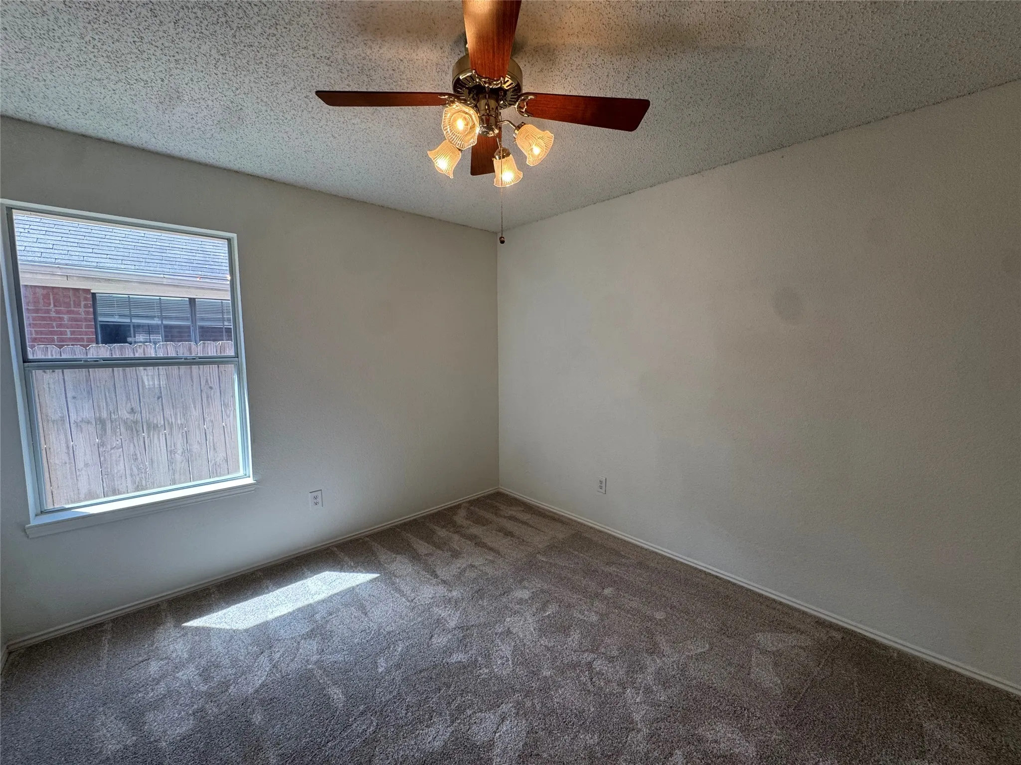 Carpeted flooring, ceiling fan with integrated lighting, and a single window