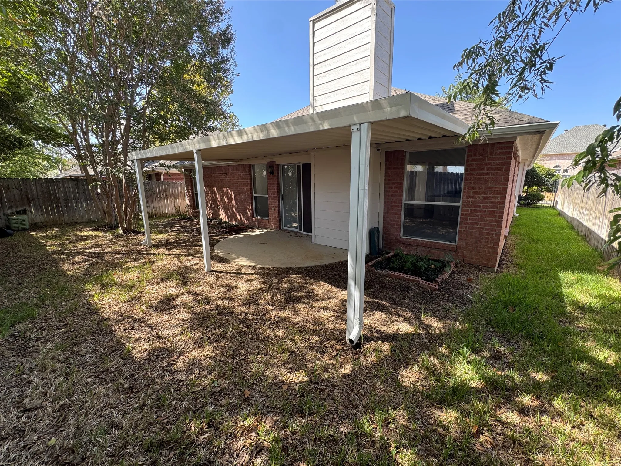 Brick exterior with covered patio, concrete slab, and fenced yard