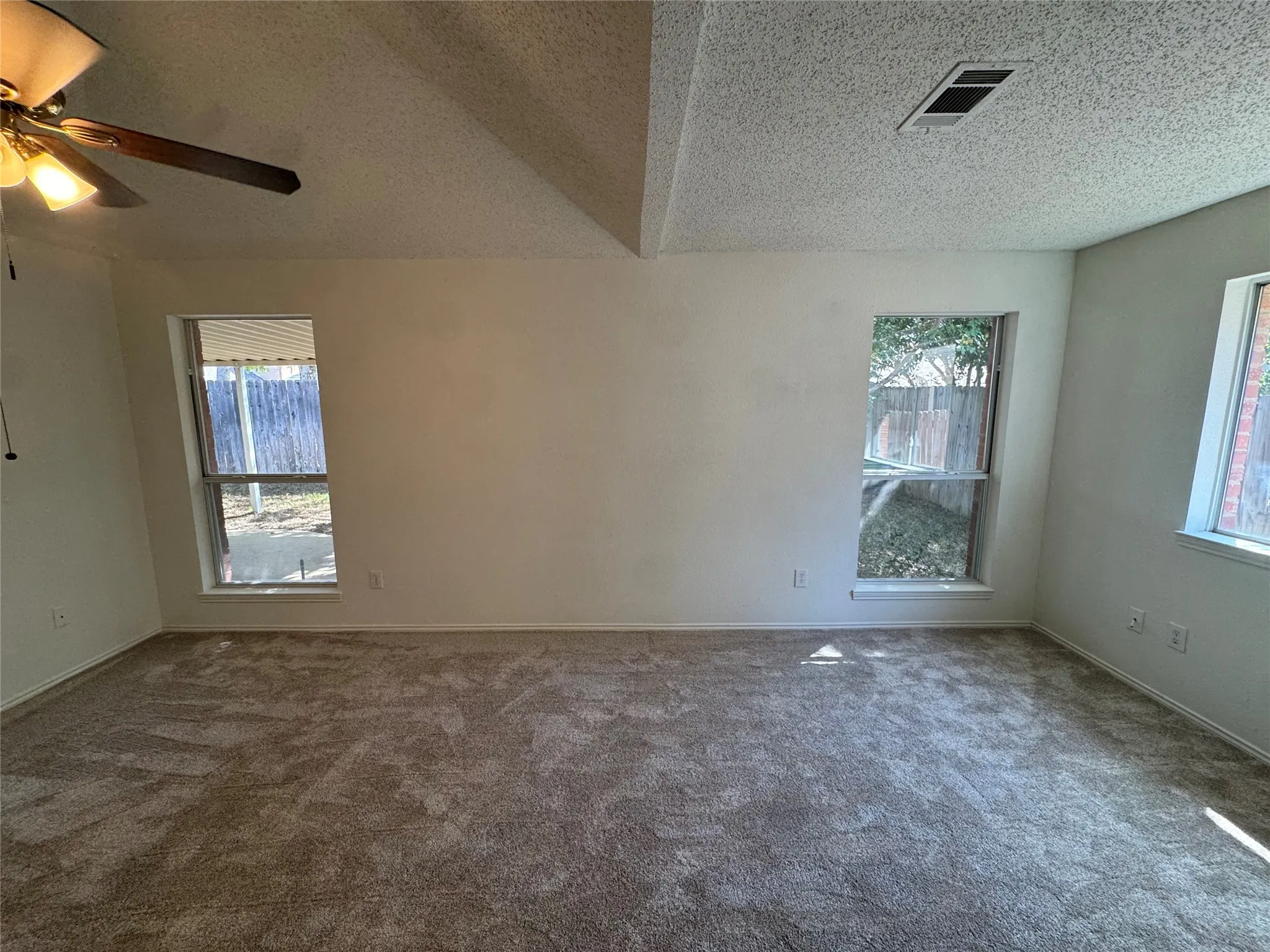 Carpeting throughout with multiple windows and a sloped ceiling