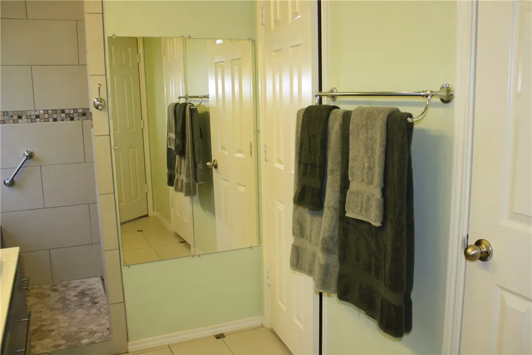 Primary closet with custom closet system is located through the door next to the mirror, and the door to the right of the towels leads to the private toilet area.