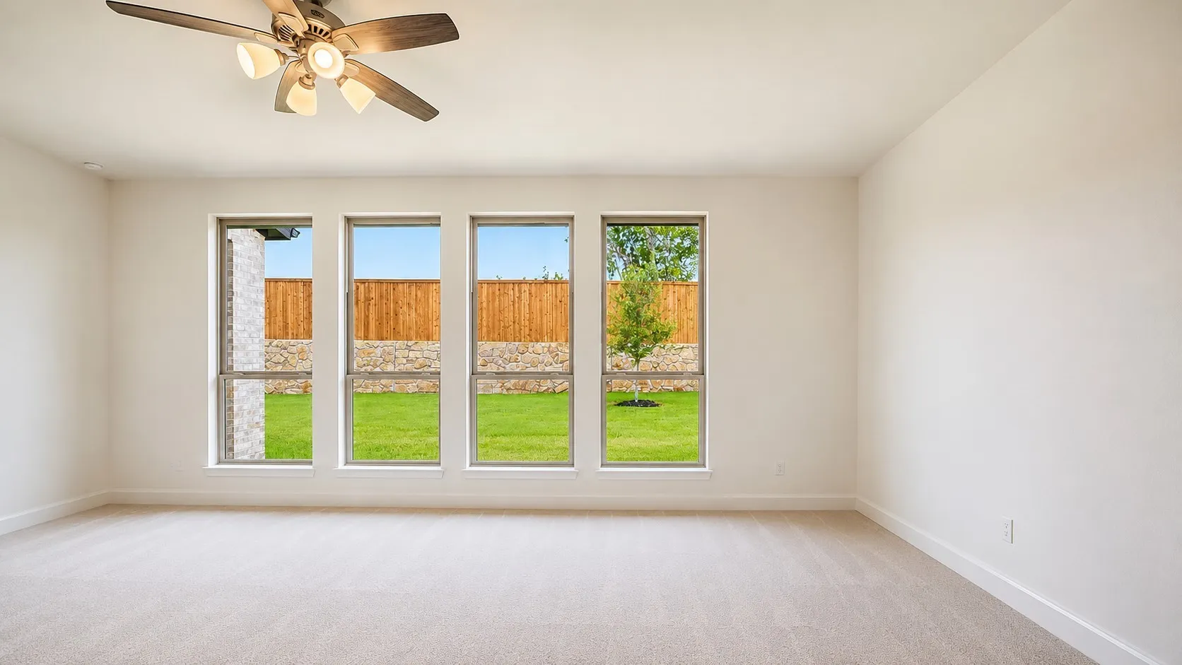 Expansive interior featuring light-colored carpeting and a ceiling fan with integrated lighting
