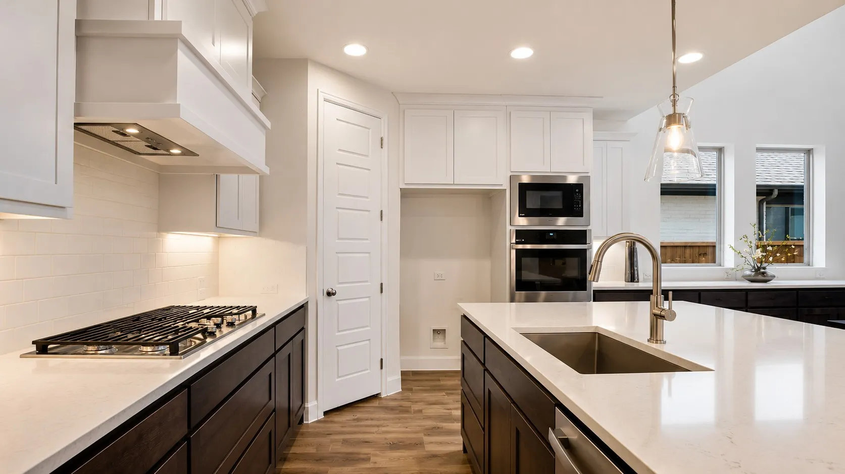 Kitchen featuring a gas cooktop, stainless steel appliances, a large island with an undermount sink, and wood-finish flooring