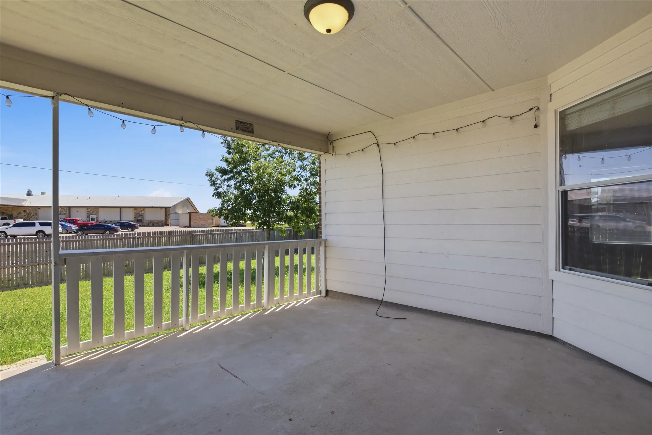 Covered patio with a concrete surface, featuring a white railing and exterior siding