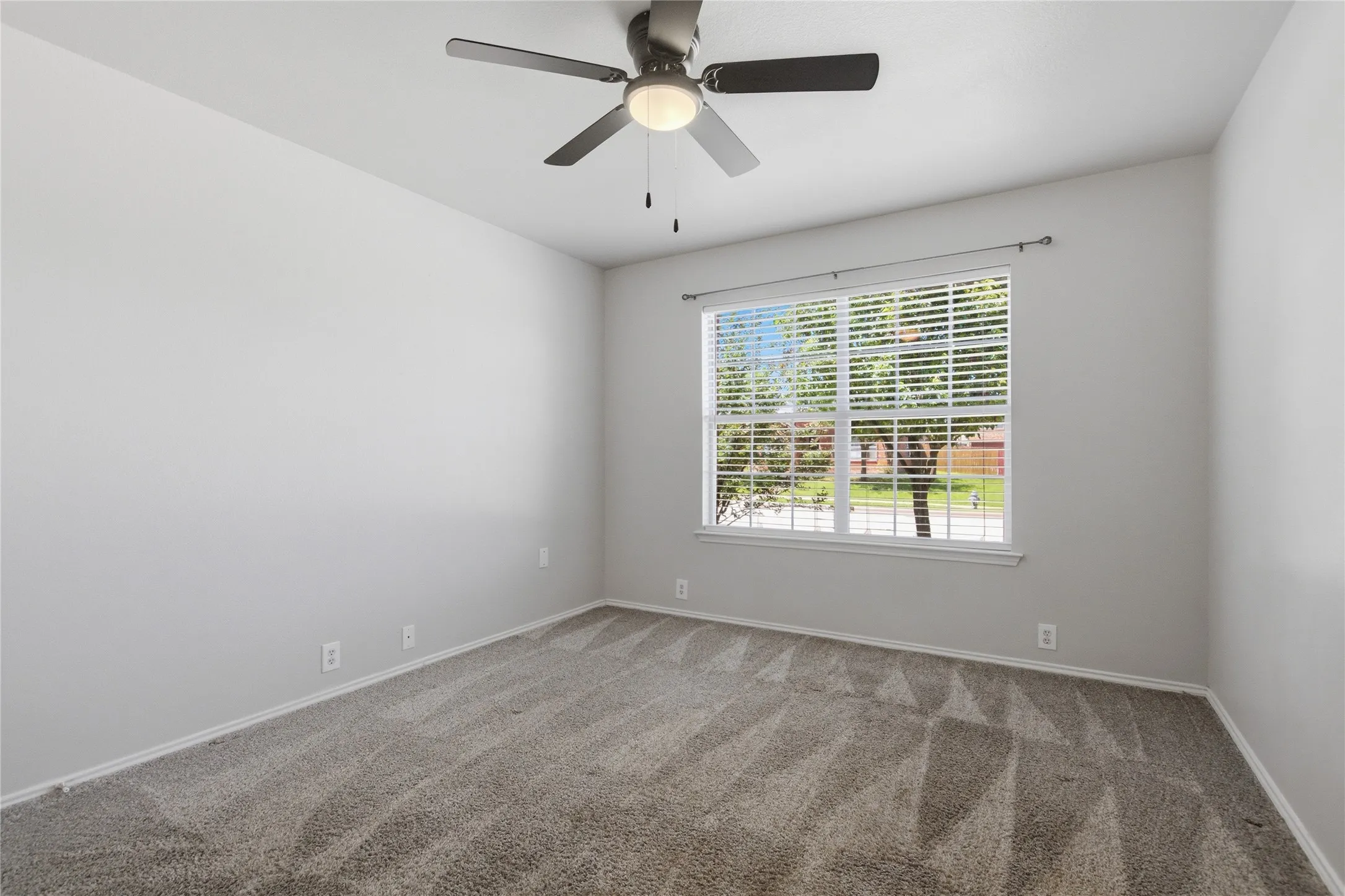Wall-to-wall carpeting, a large window with blinds, and a ceiling fan with integrated lighting