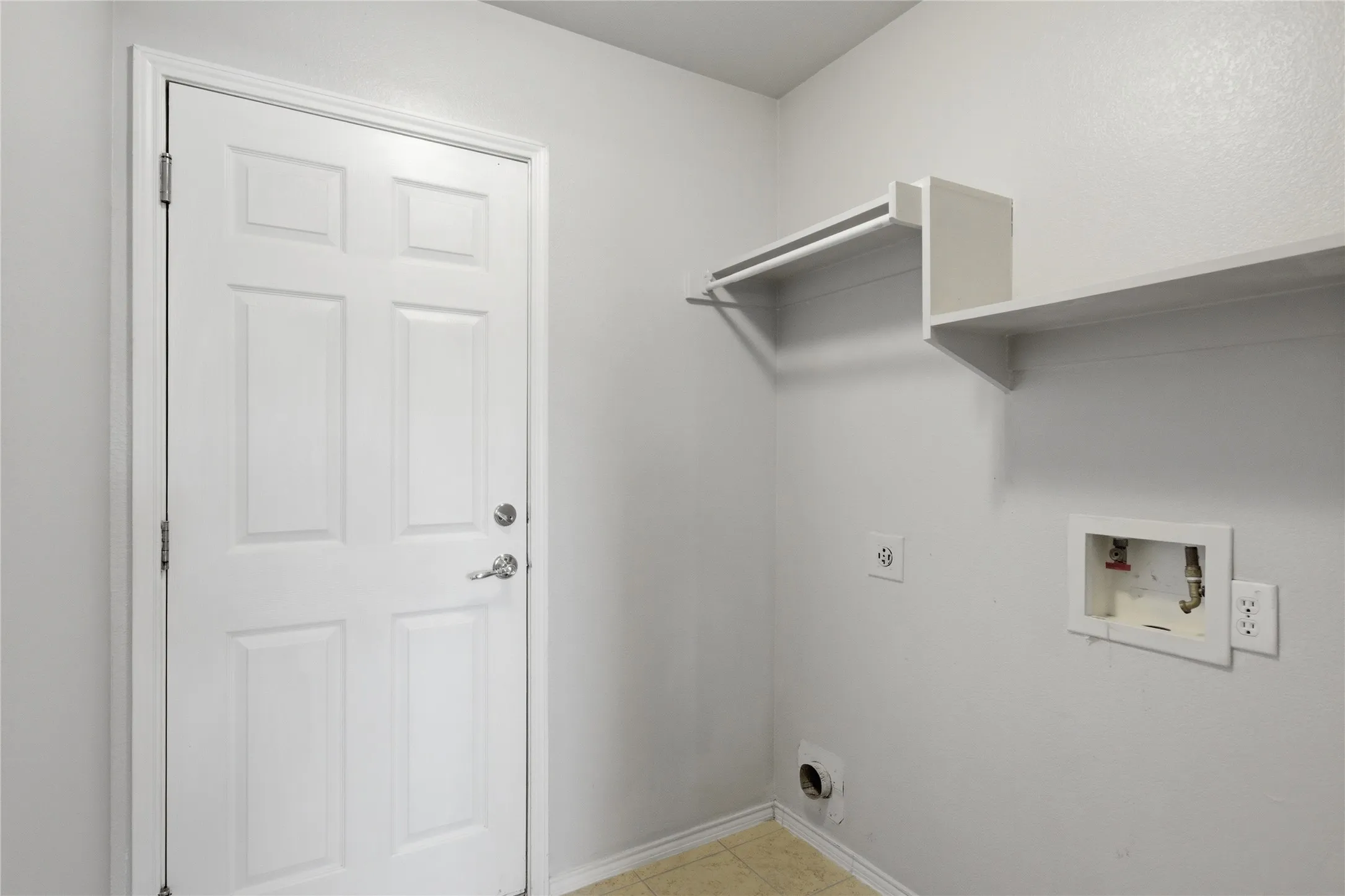 Utility space featuring a paneled door, integrated shelving, and a garment rod