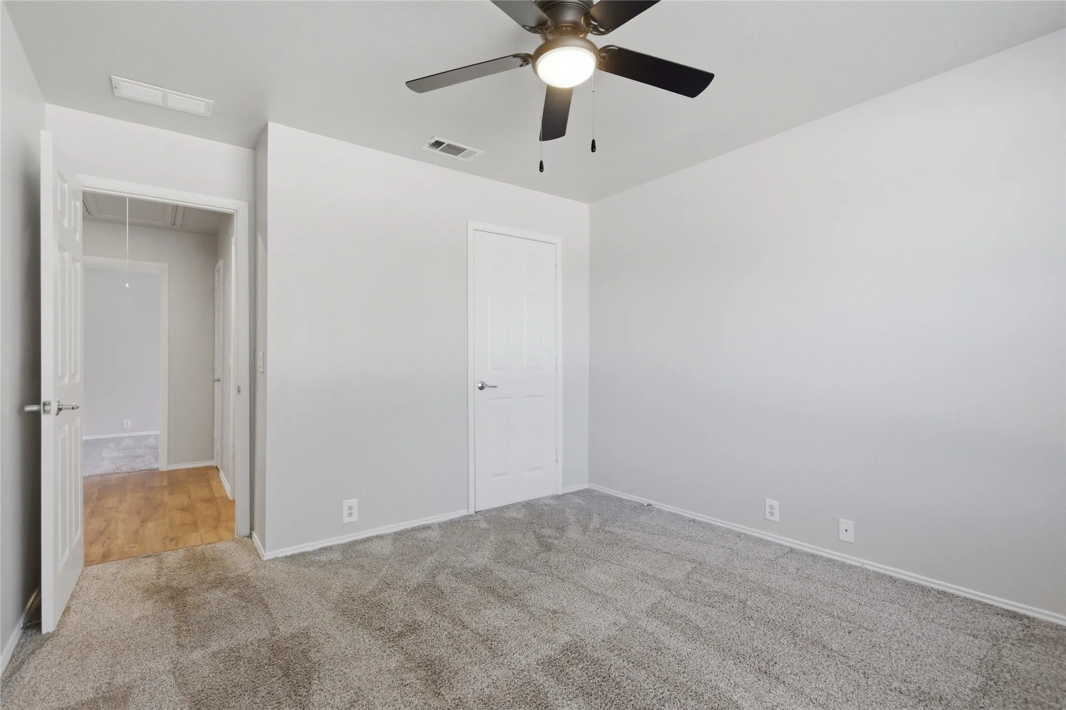 Carpeted room with a ceiling fan light fixture, light gray walls, and white trim