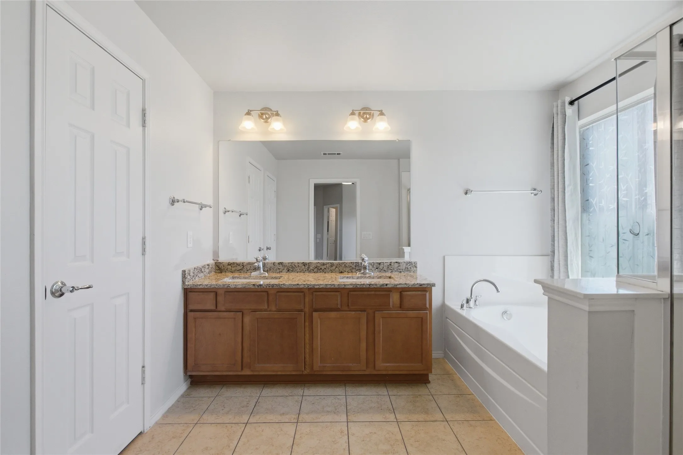 Double vanity with granite countertop, integrated sinks, and ample storage cabinetry
