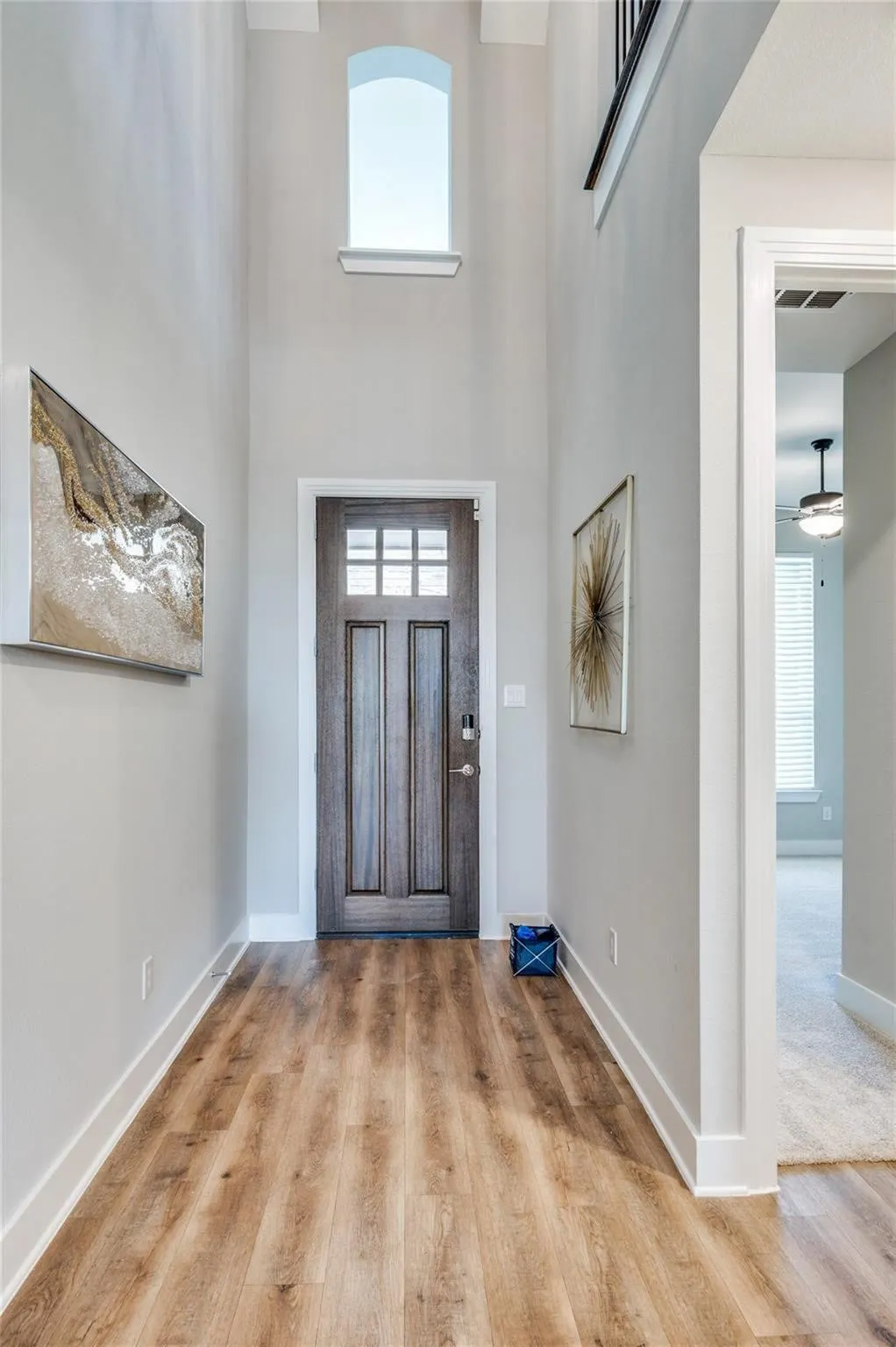Two-story foyer featuring an arched window, wood-finish flooring, and a dark wood entry door with glass panels