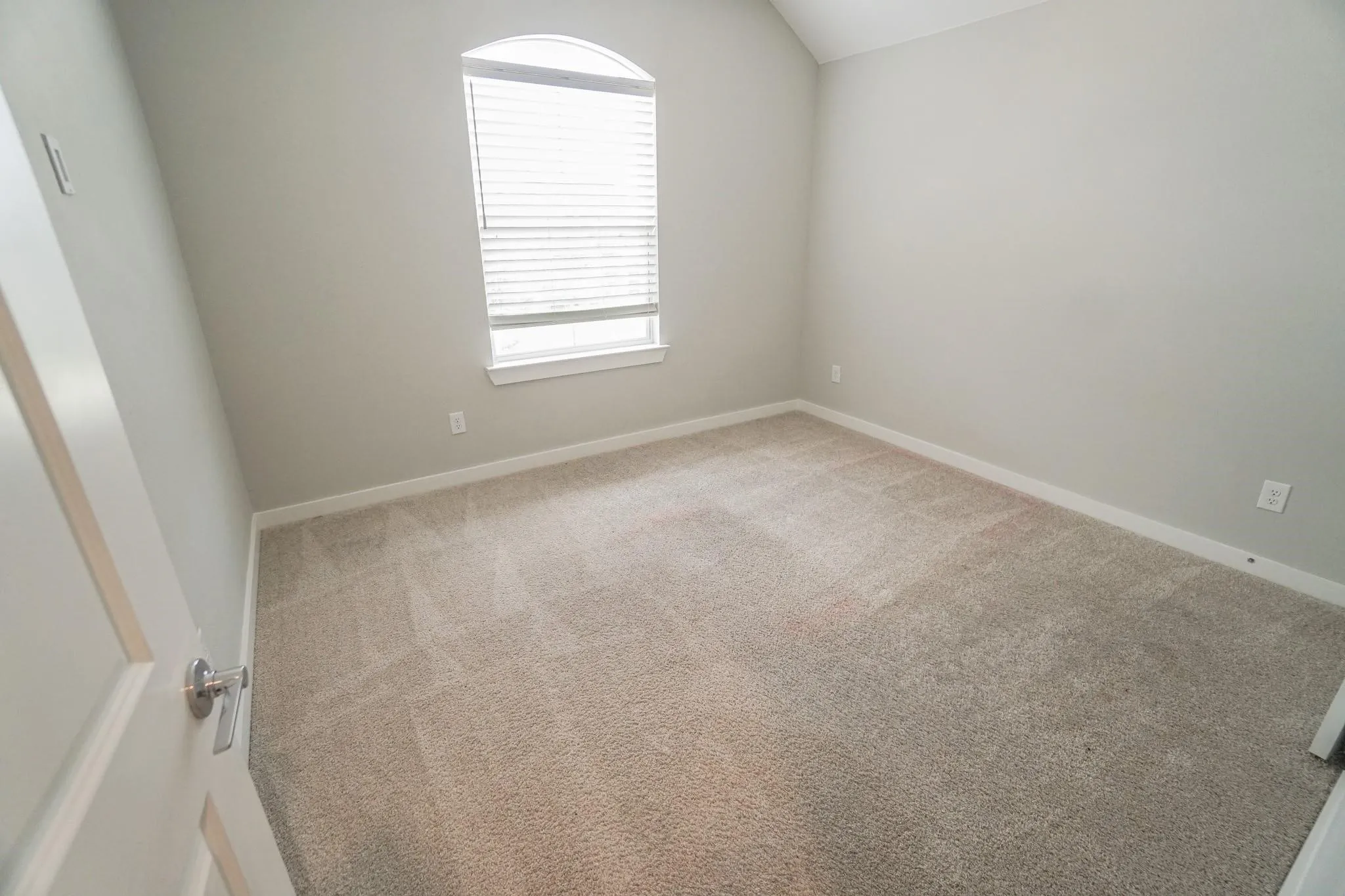 Carpeted room featuring a single arched window with blinds
