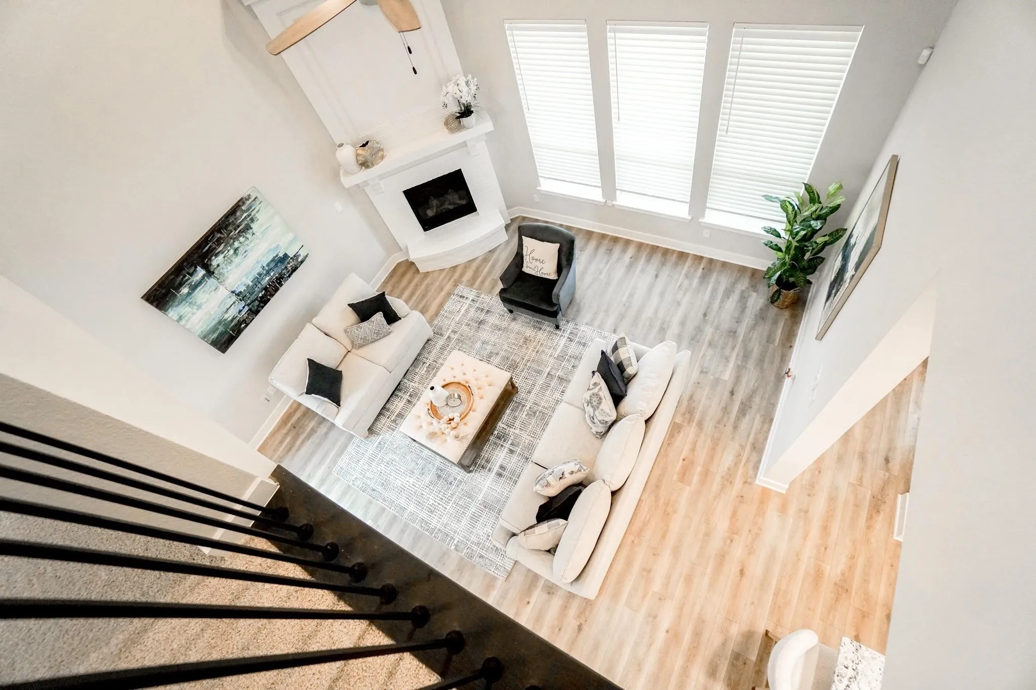 Two-story living area with a fireplace, vaulted ceiling with a fan, wood-finish flooring, and multiple windows