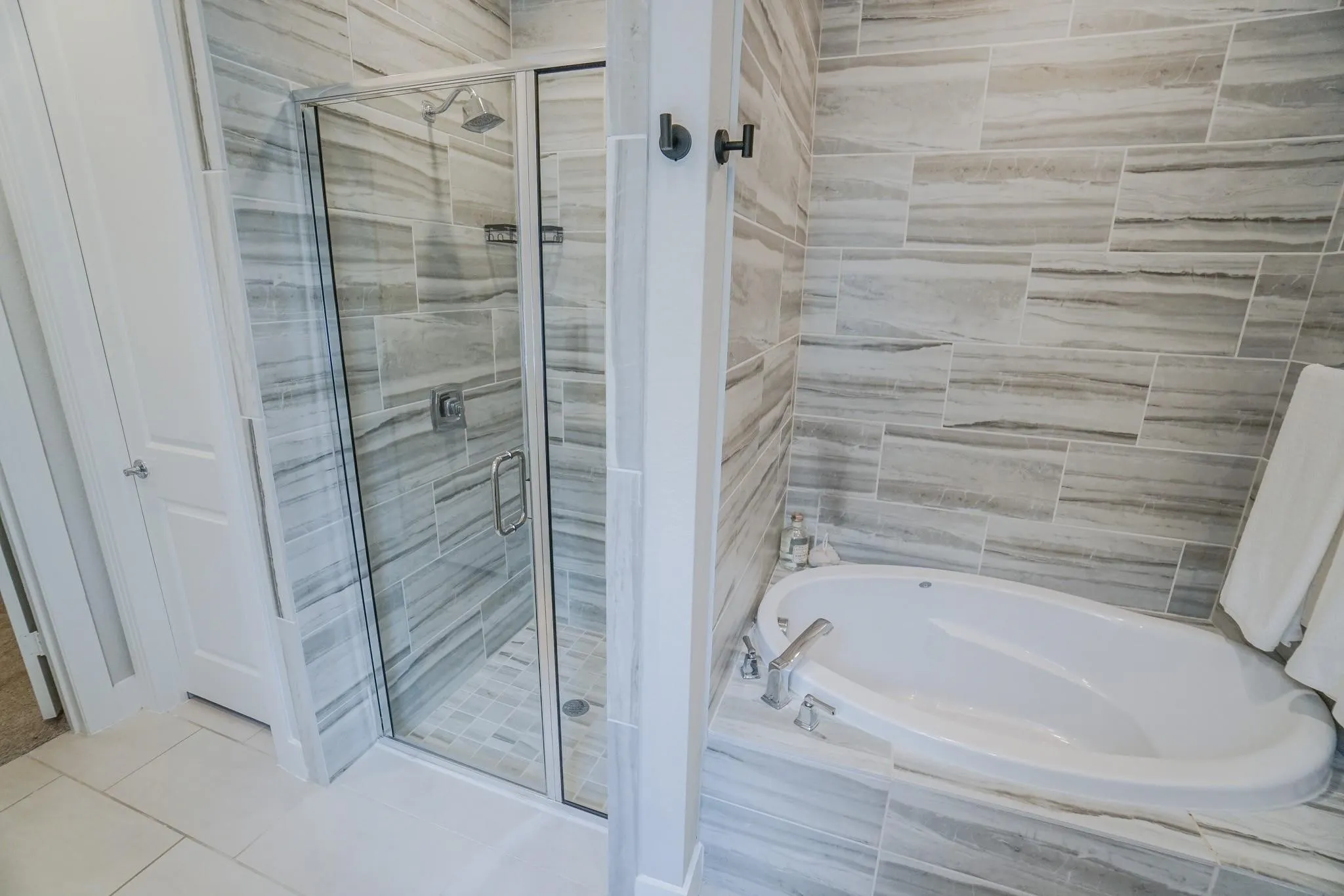 Freestanding soaking tub, glass-enclosed shower, and floor-to-ceiling tile work