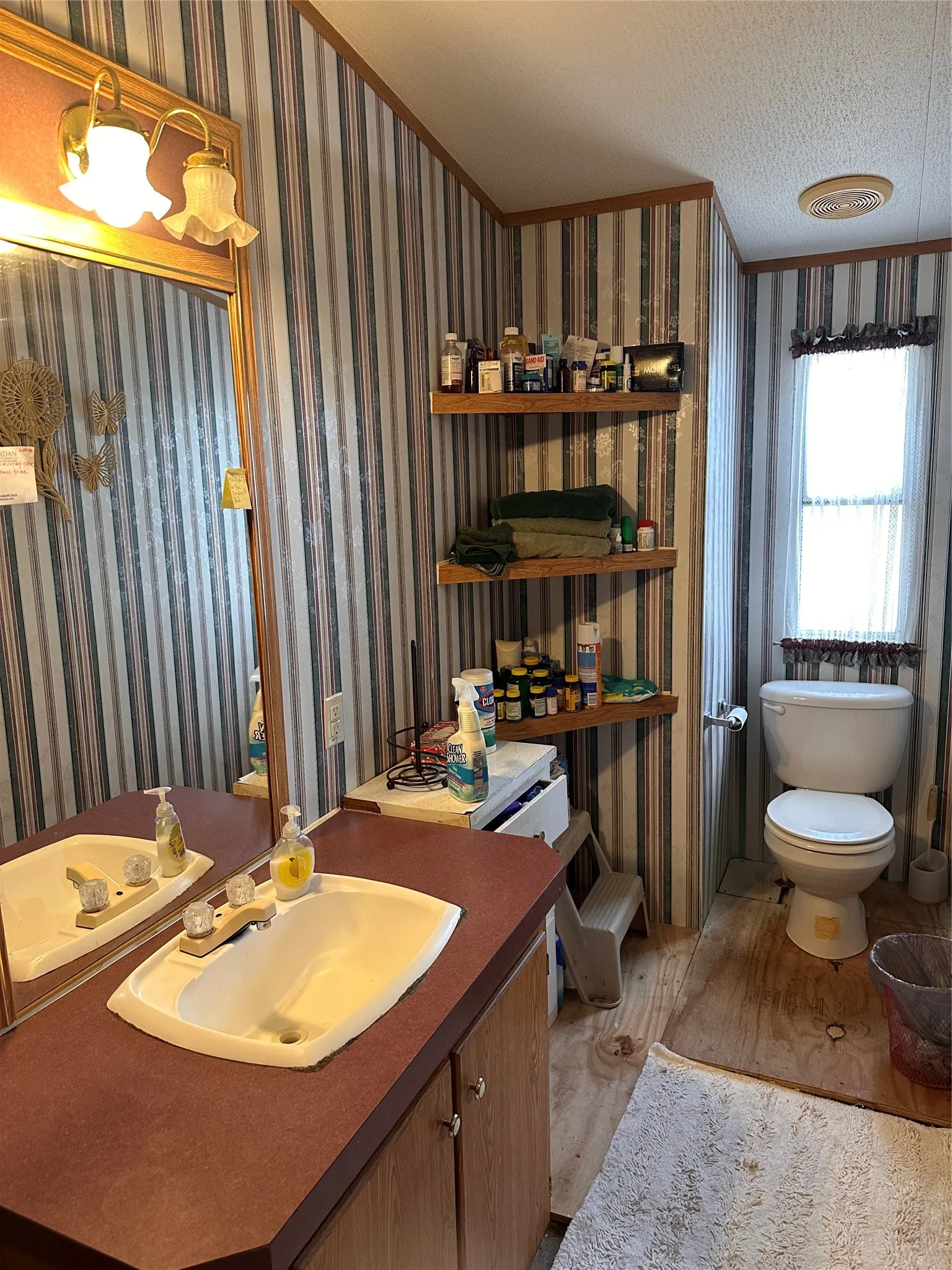 Vanity with integrated sink, wall-mounted mirror, overhead lighting fixture, and a toilet
