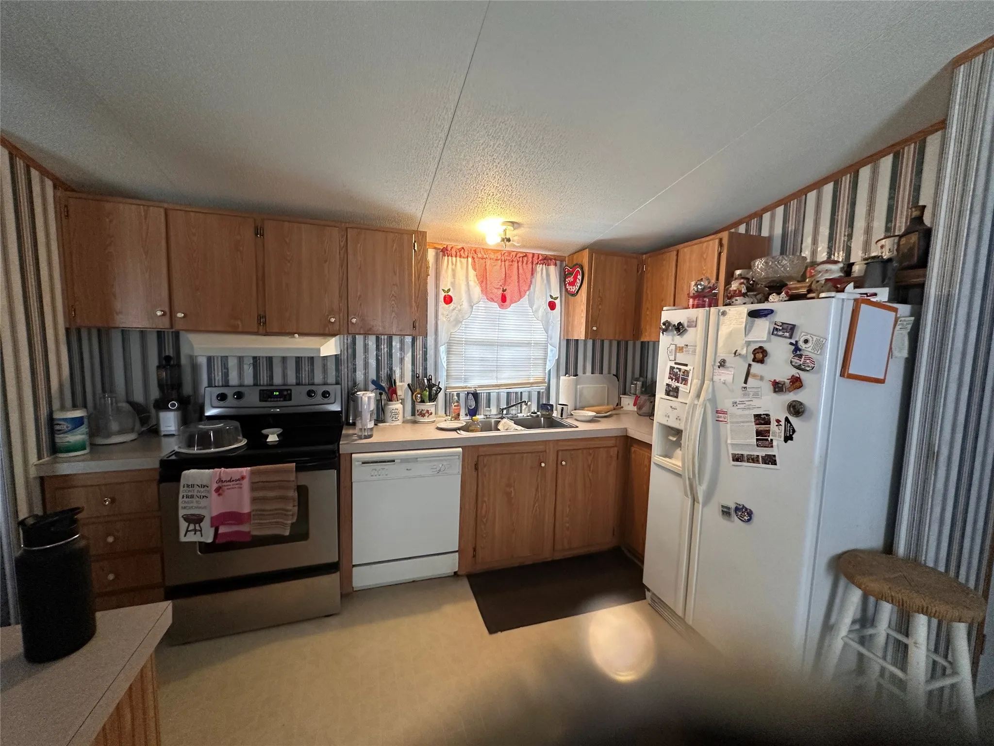 kitchen with wood-finish cabinetry, stainless steel range, and white dishwasher