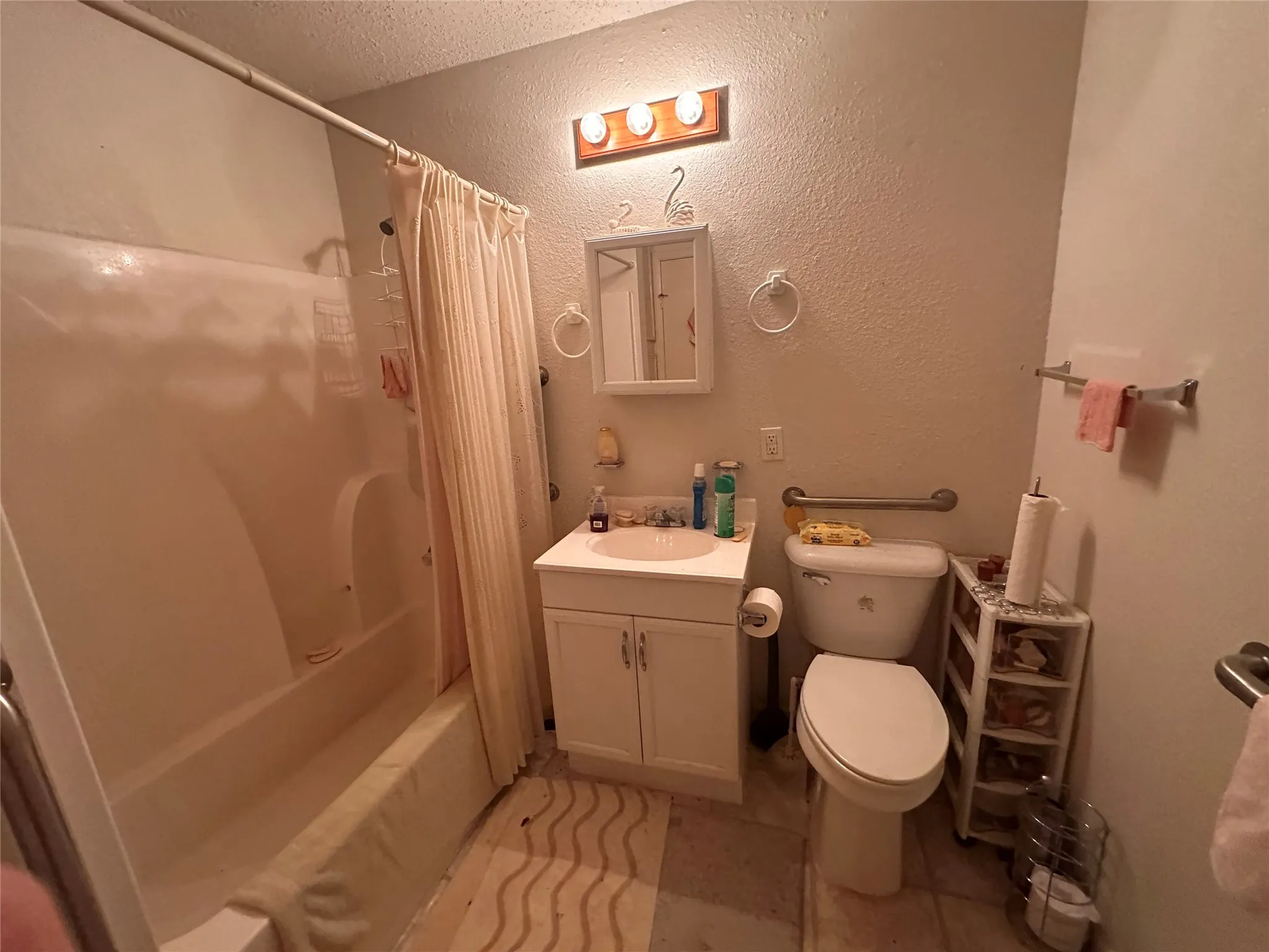White single vanity white shower-over-tub combination, and wall-mounted grab bars