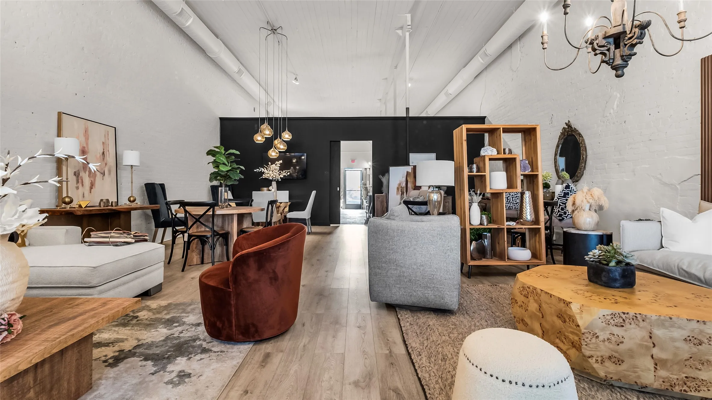 Spacious interior with high ceilings, exposed ductwork, wood-finish flooring, and industrial-style lighting fixtures