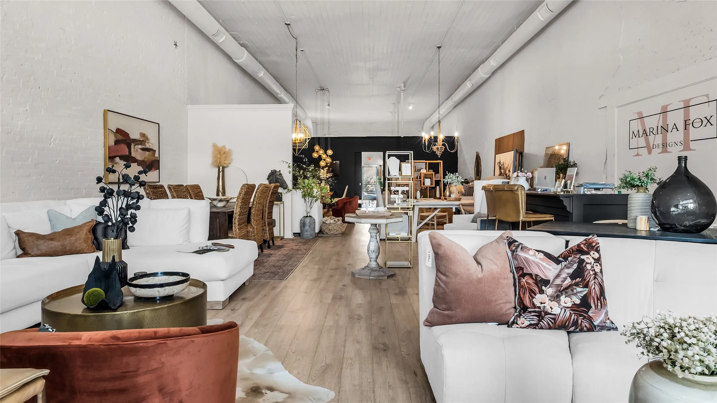 High ceilings with exposed ductwork, wood-finish flooring, recessed lighting, and a white brick-textured wall