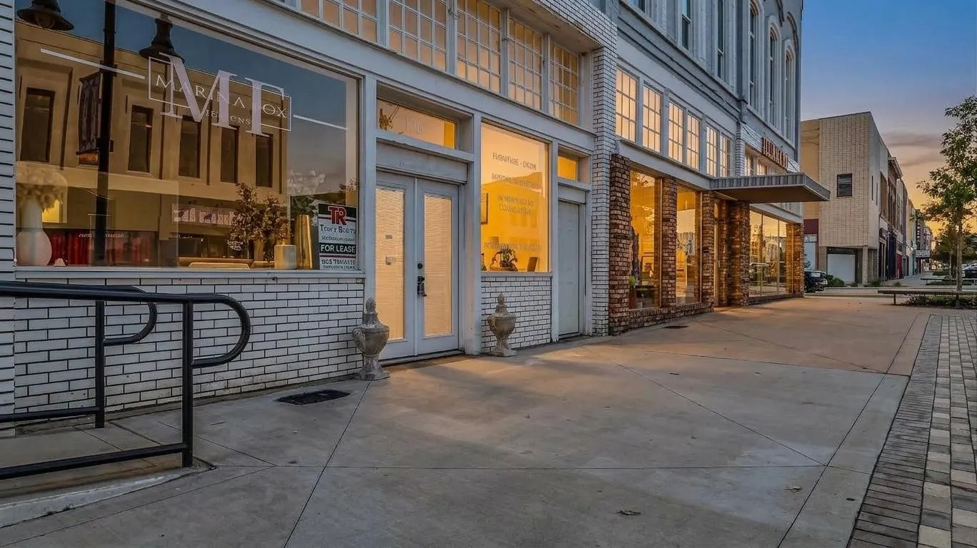 Exterior featuring white brick, large storefront windows, and double entry doors