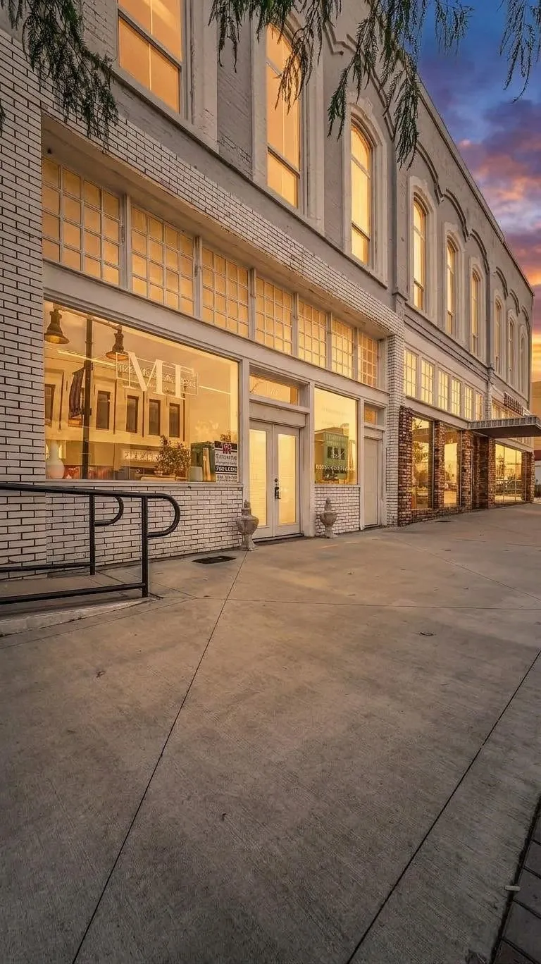 Masonry brick exterior with arched windows, large storefront windows, double-door entry, and concrete sidewalk