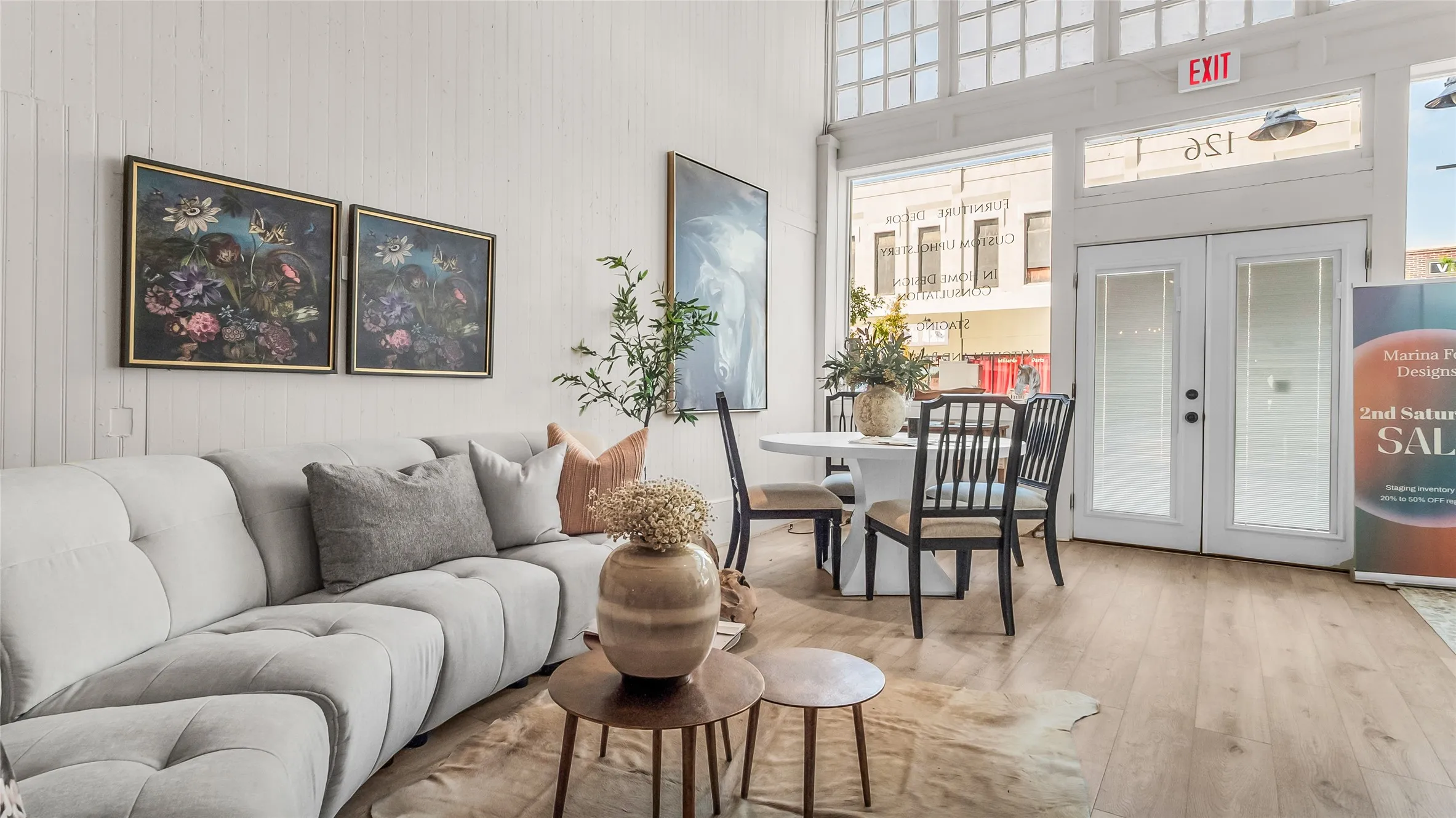 High ceilings with transom windows, wood-finish flooring, white paneled walls, and a glass-paneled double door entry