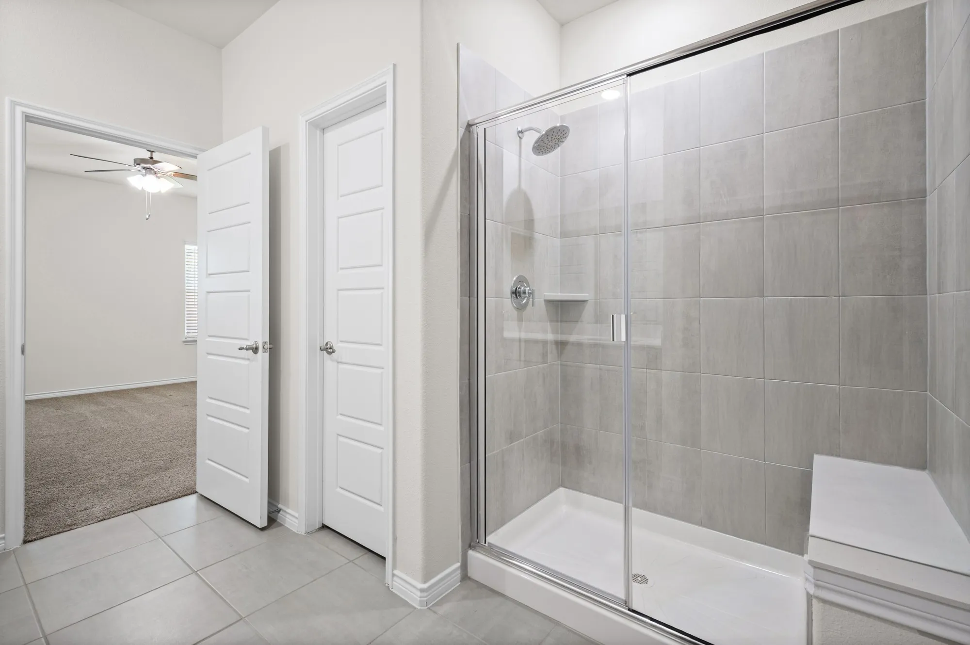 Glass-enclosed shower with a built-in bench, rain showerhead, and tiled walls