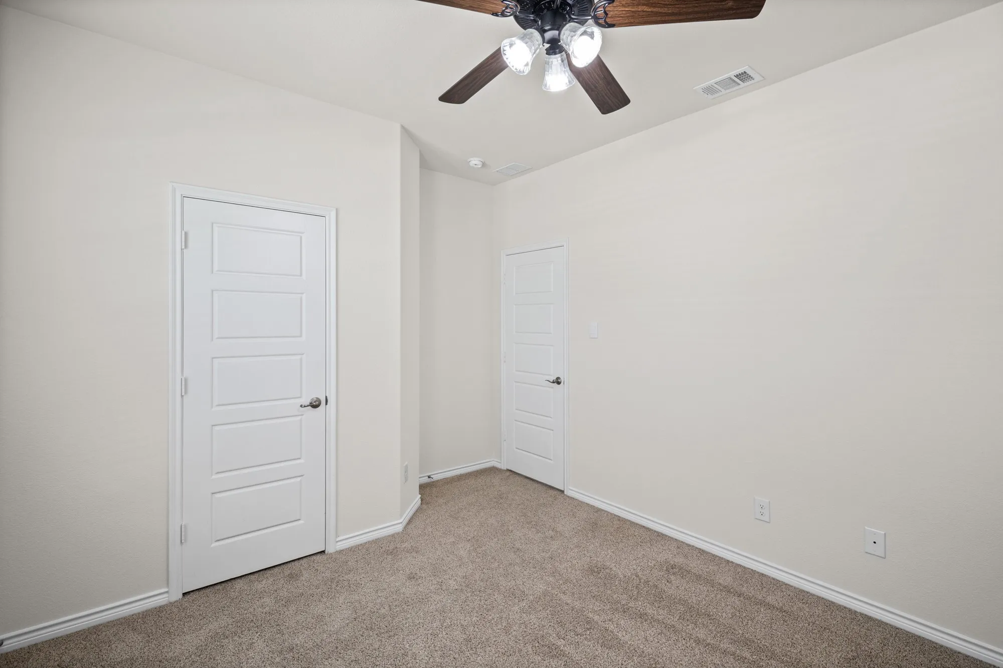 Recessed ceiling fan with integrated lighting, paneled interior doors, light-toned walls, and carpet flooring