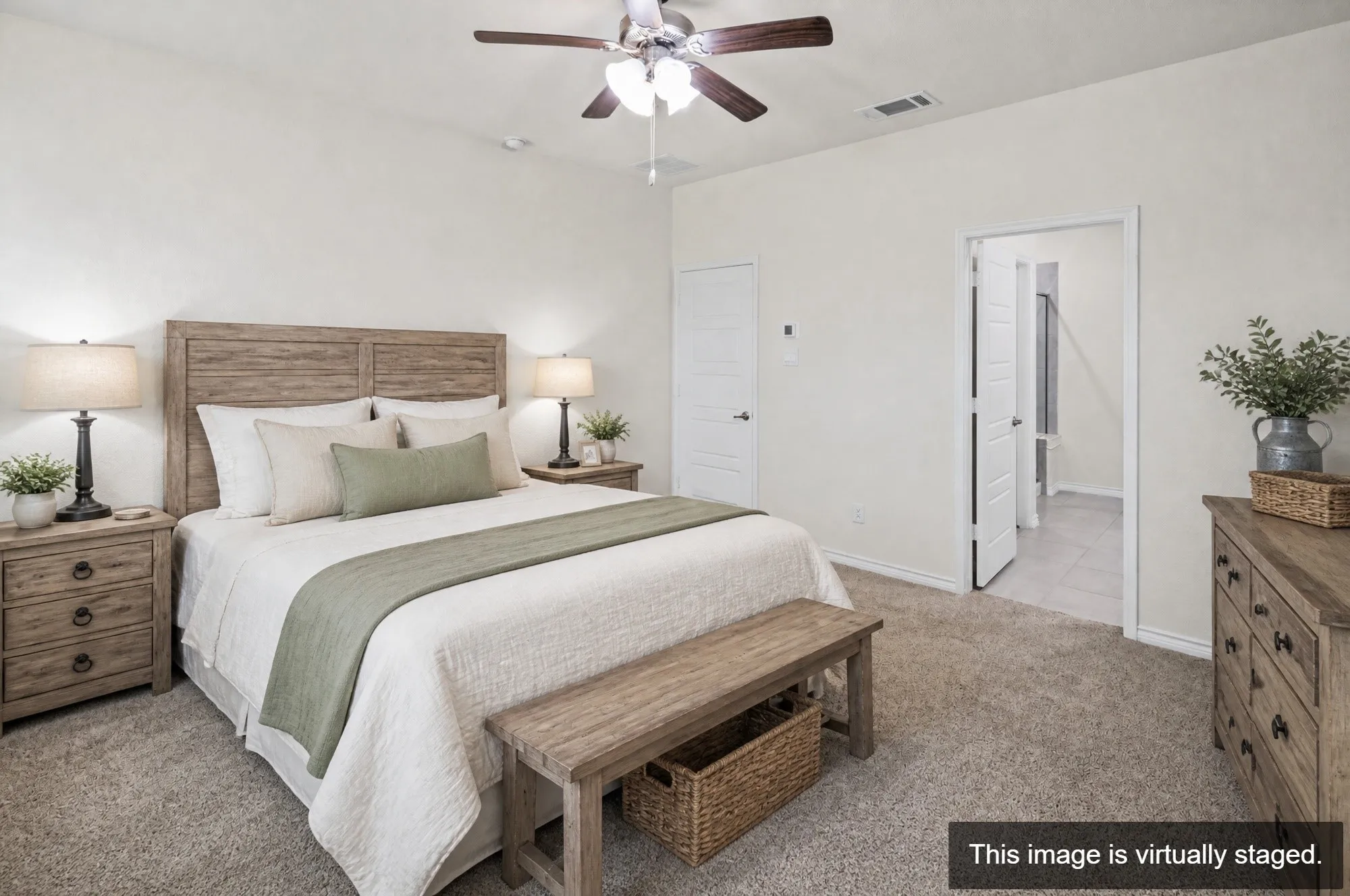 Primary bedroom suite featuring a wood-finish headboard, ceiling fan with integrated lighting, neutral carpeting, dual nightstands with task lighting, and an attached ensuite bathroom with glass-enclosed shower